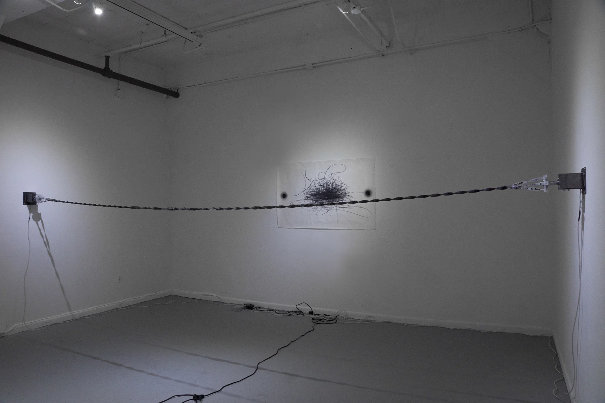 " Entangled Descriptions " , 2017 Stepper motors, texts painted with dark gray plaster on three translucent silicone rubber bands, Arduino (programming board), Dimensions variable Courtesy Hyunjung Rhee & Carrie Able Gallery 