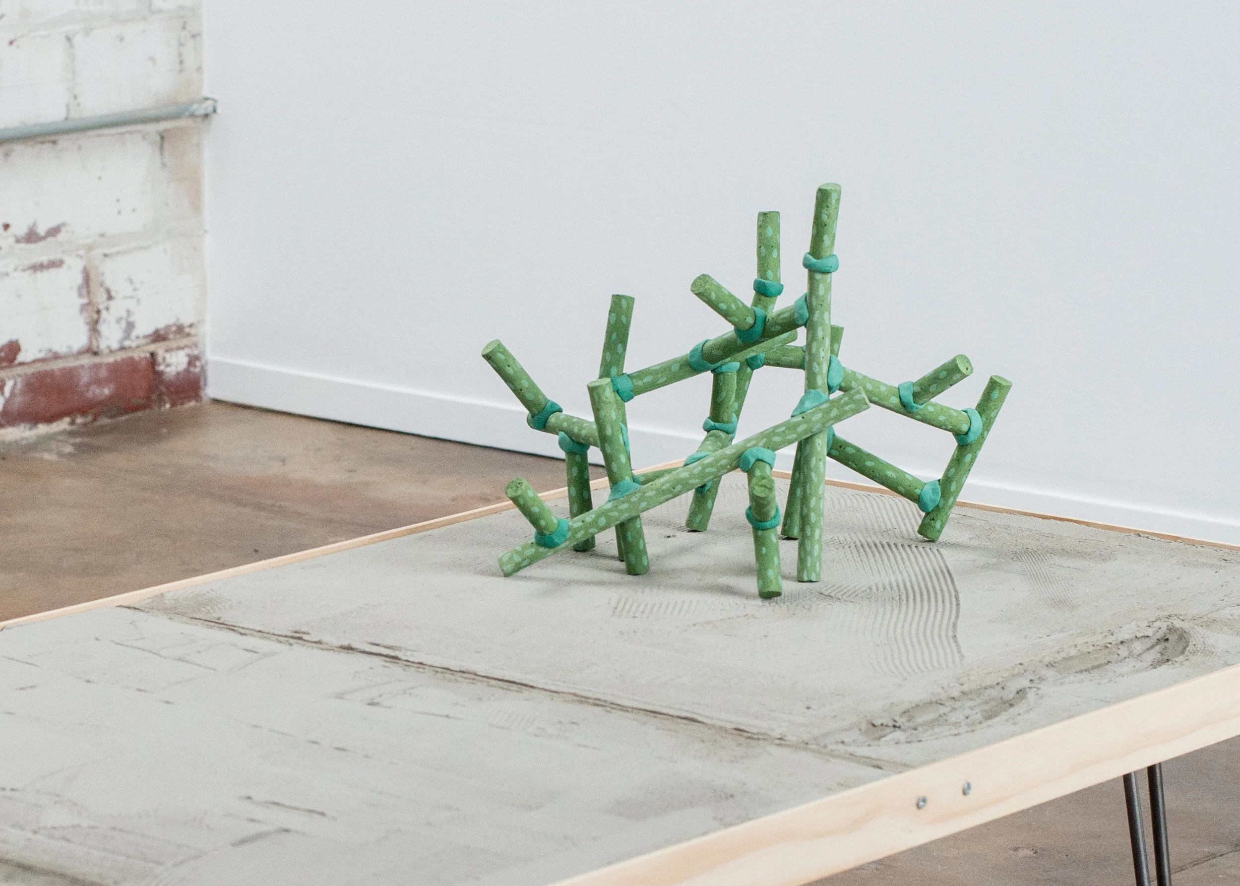 Jon P. Geiger, Topo Table, 2017 Mortar, plywood, hardwood, steel. 16" x 28" x 48". and Blossom # 2, 2017. Stoneware, underglaze, Magic Sculp. 12" x 18" x 18”. 2017