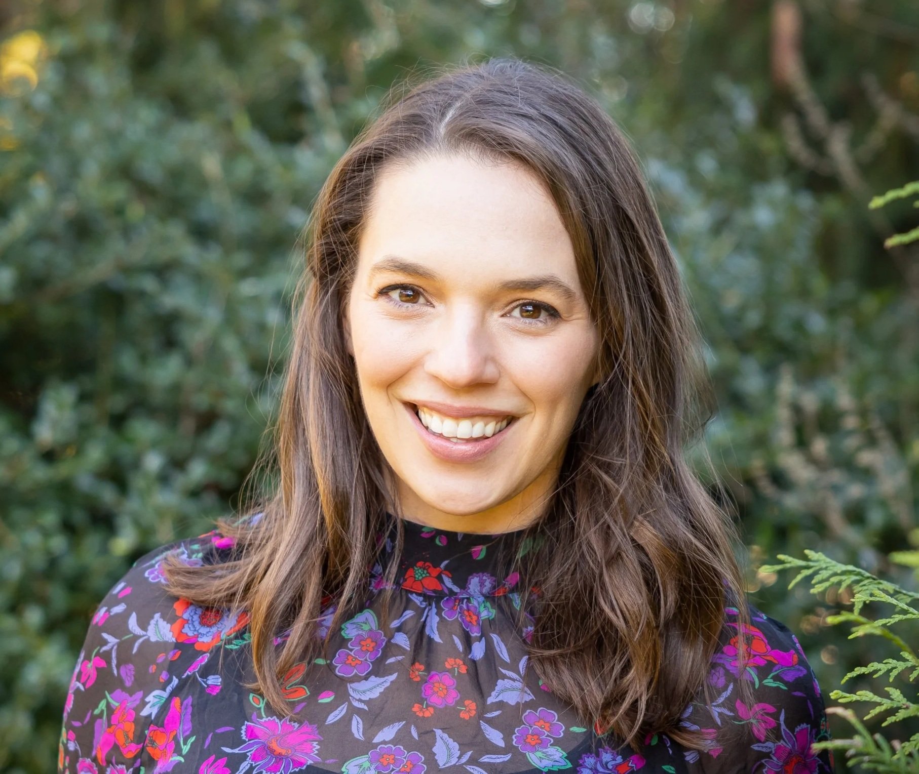 Dr. Stephanie Ernestus is an Associate Professor and Clinical Psychologist. She provides therapy to children and families. This is a picture of her face. She is wearing a floral shirt.