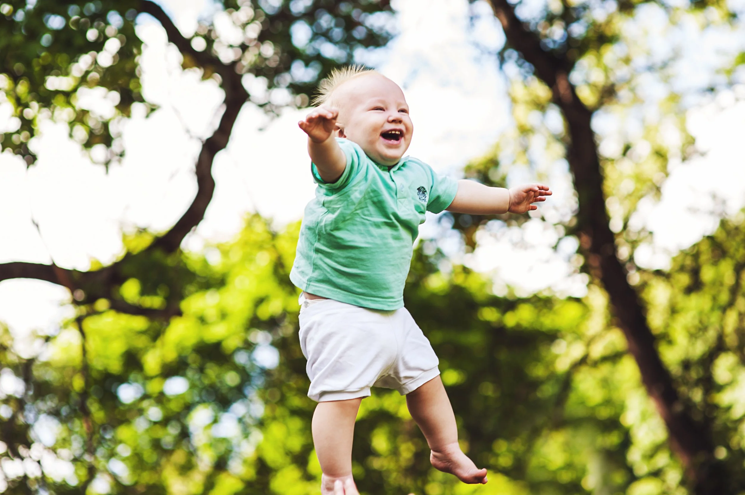 Laughing child being lifted in the air outdoors