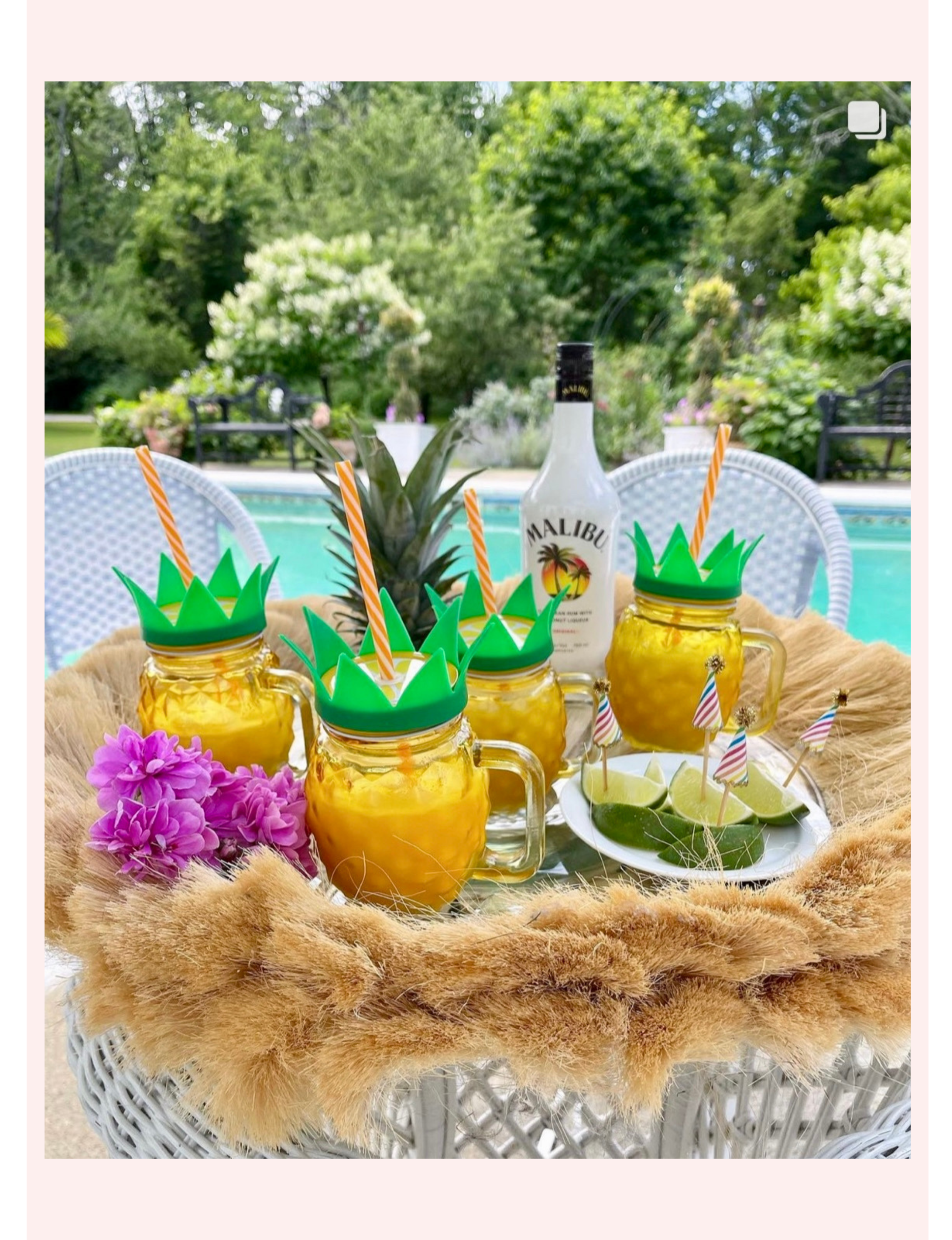 Pineapple-shaped mason jar cups outfitted with green crown-style lids and striped straws served alongside a bottle of Malibu Caribbean Rum, fresh lime slices