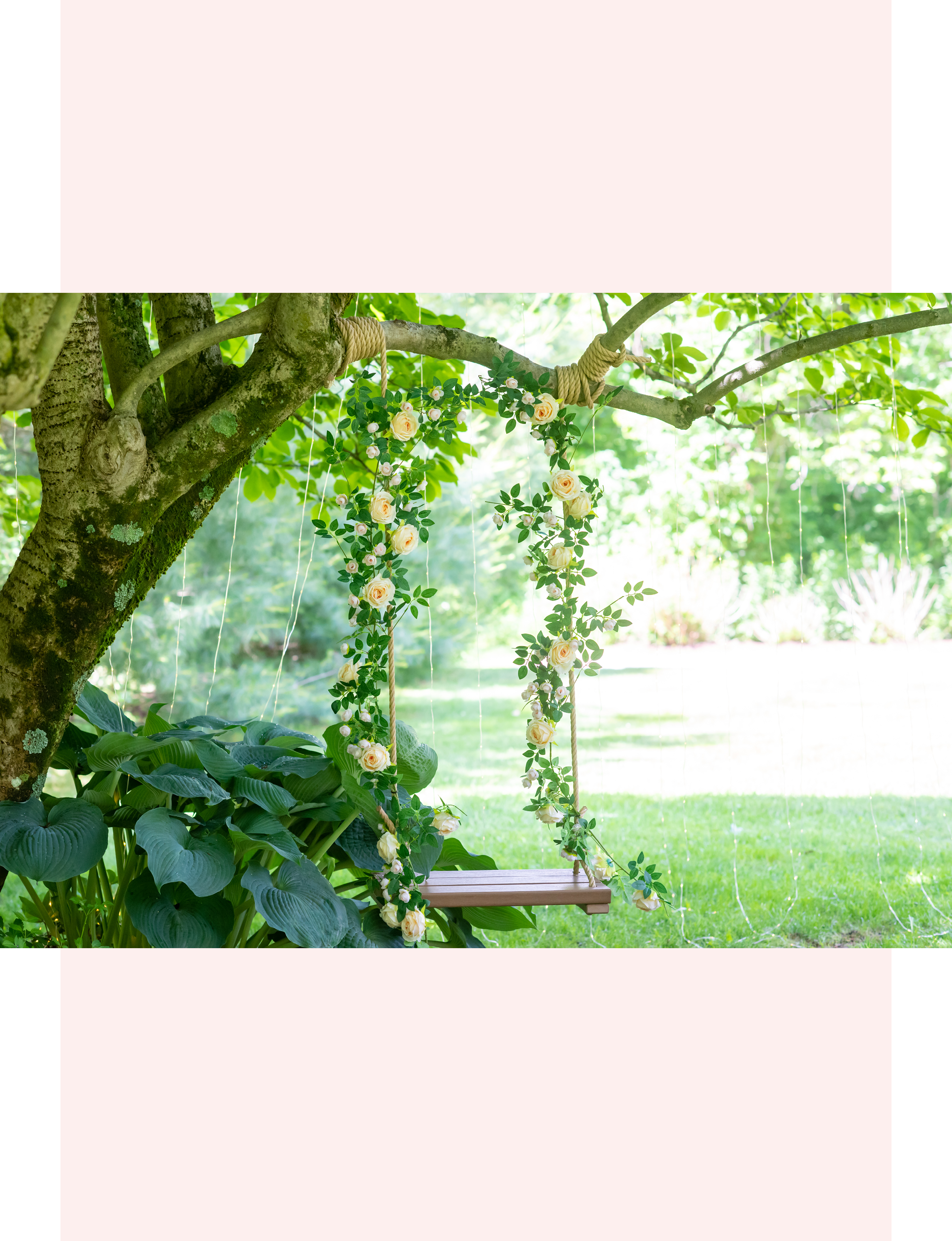 eucalyptus flower garland adorned with champagne roses and greenery wrapped around the ropes of a rustic wooden tree swing
