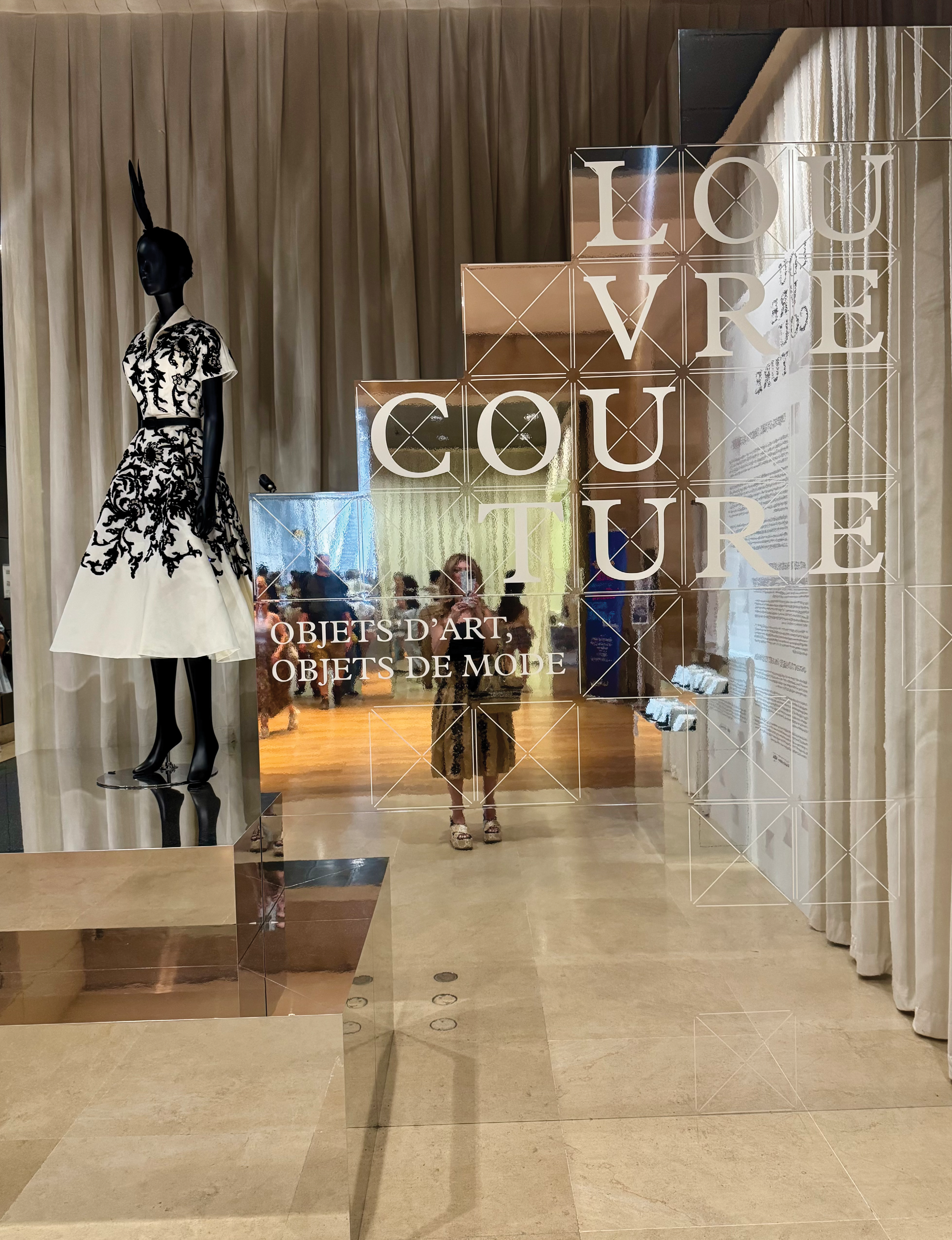 a striking Christian Dior haute couture dress displayed as part of the landmark Louvre Couture exhibition at the Musée du Louvre in Paris