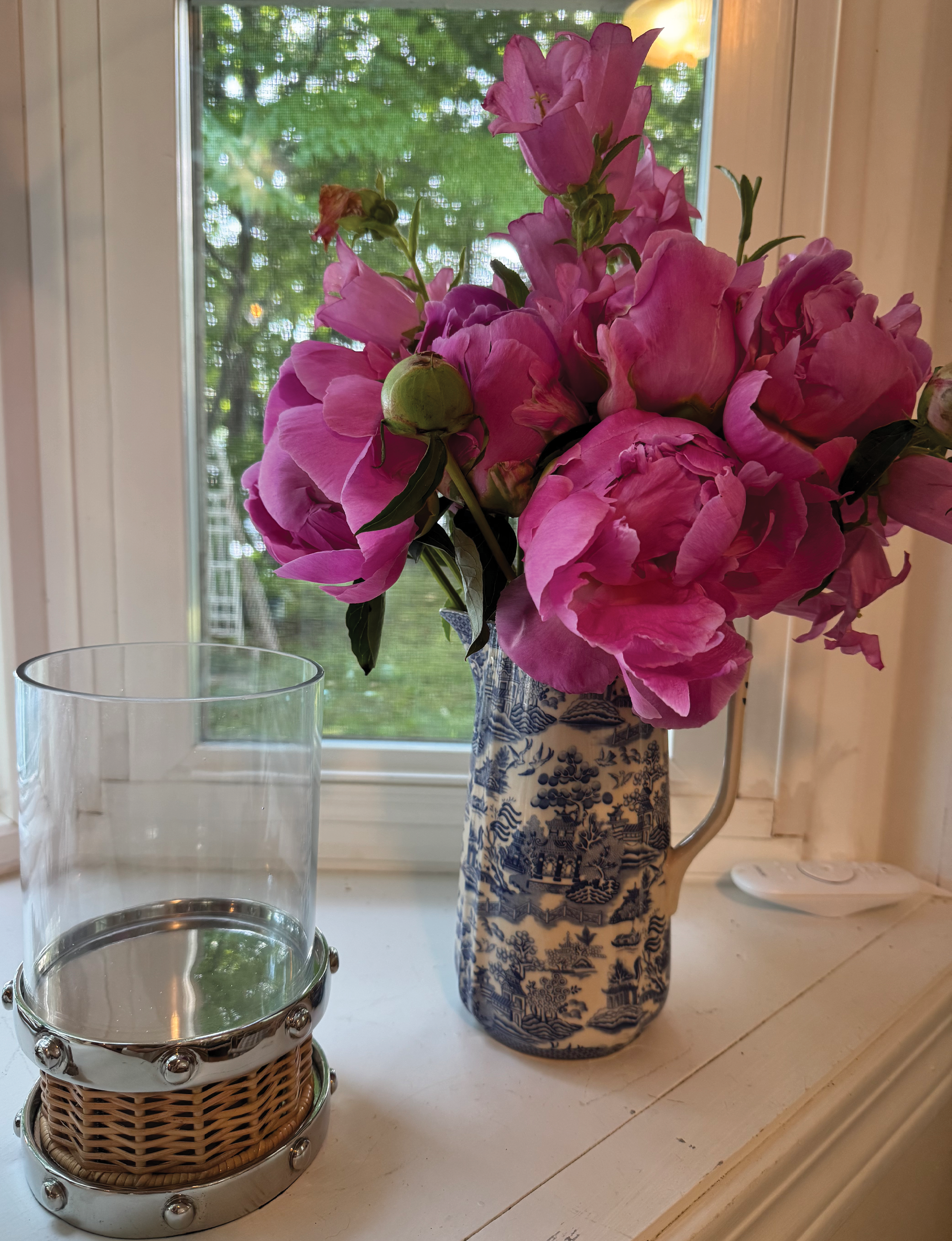 floral arrangement with pink peonies and bellflowers in a blue and white Chinoiserie ceramic pitcher on a windowsill
