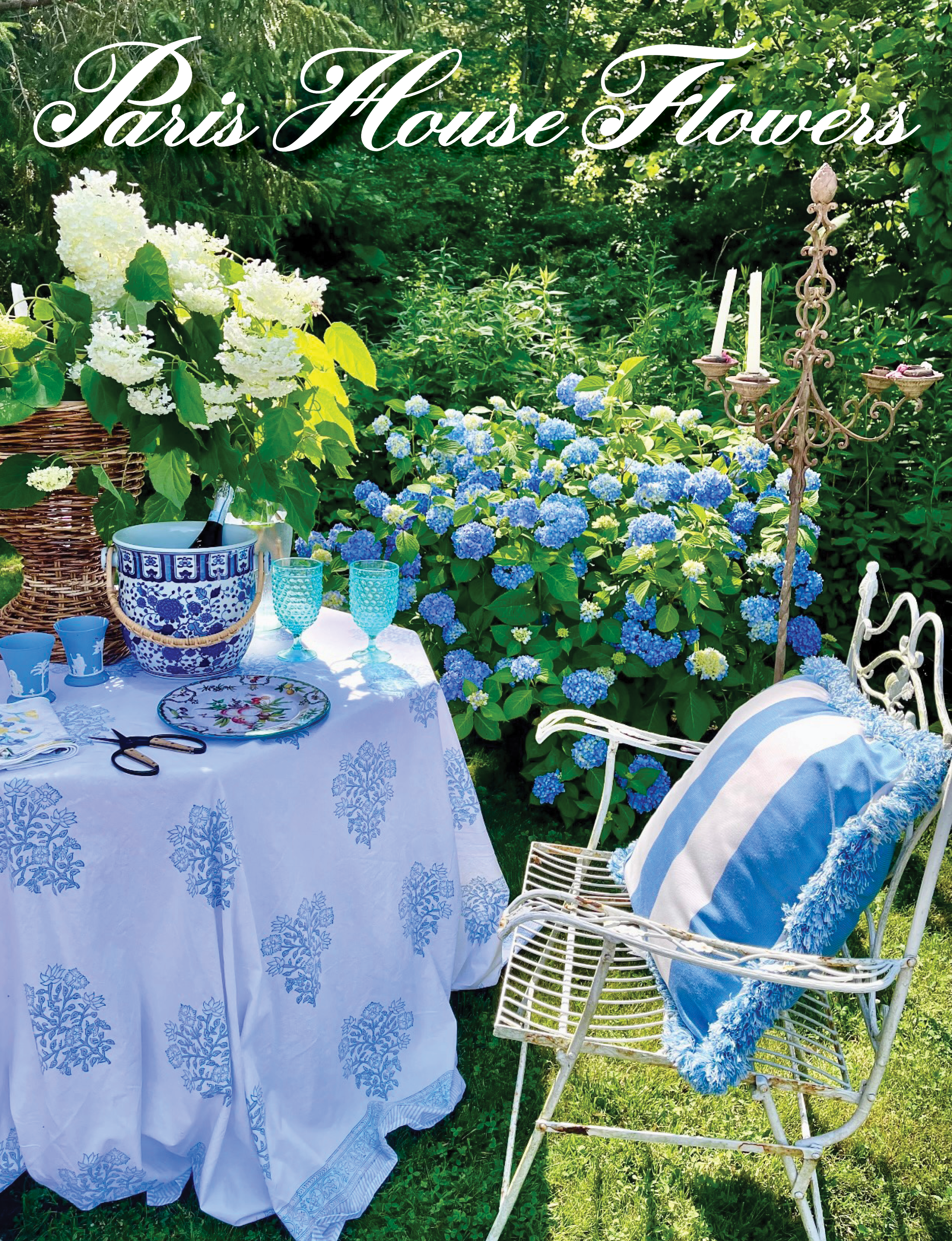 garden scene with blue hydrangeas, blue tablecloth, blue glasses, blue and white striped pillow and blue and white ice bucket