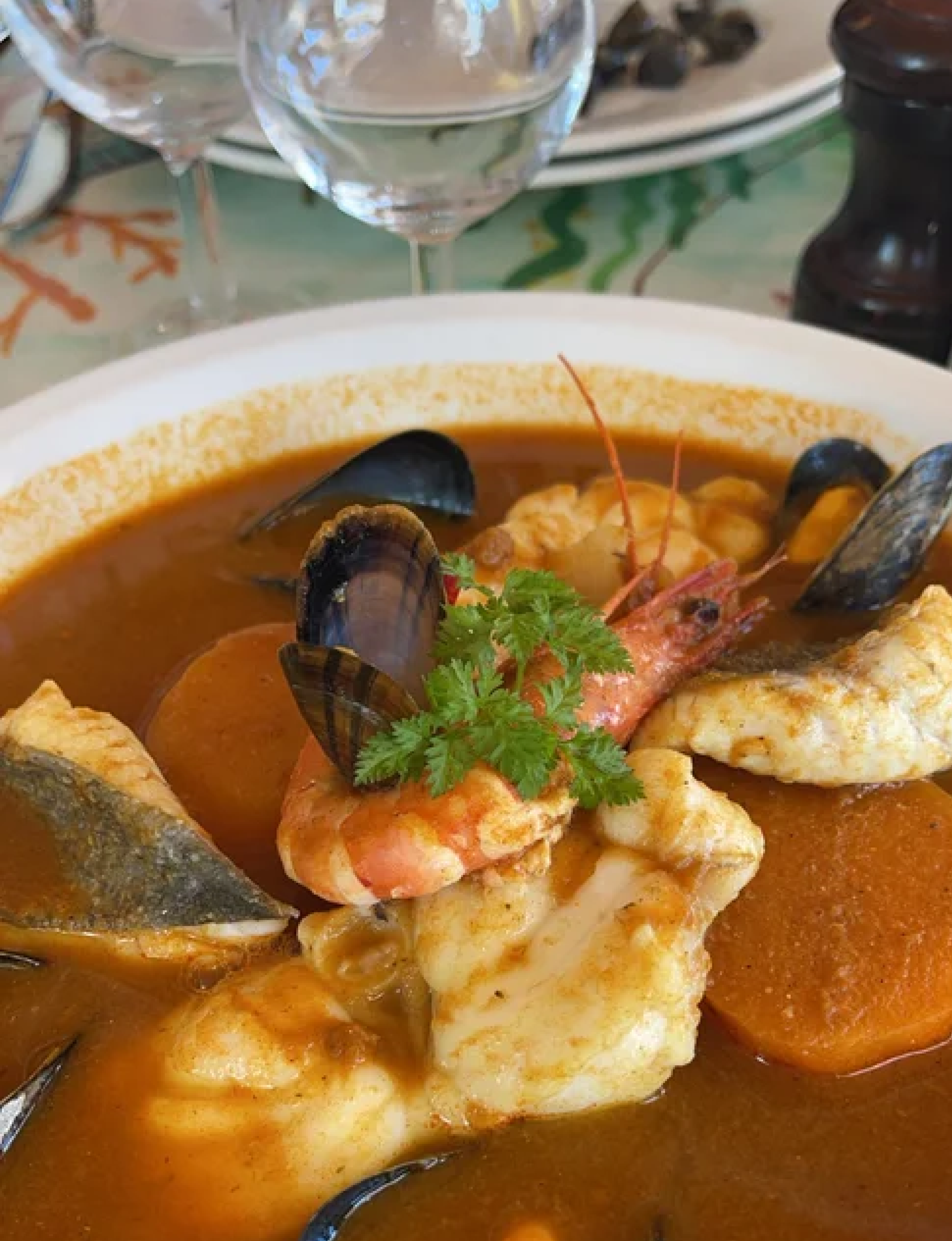 a platter of fresh oysters served on crushed ice with a halved lemon in France featuring a rich saffron-infused broth loaded with assorted fish, shrimp, and mussels