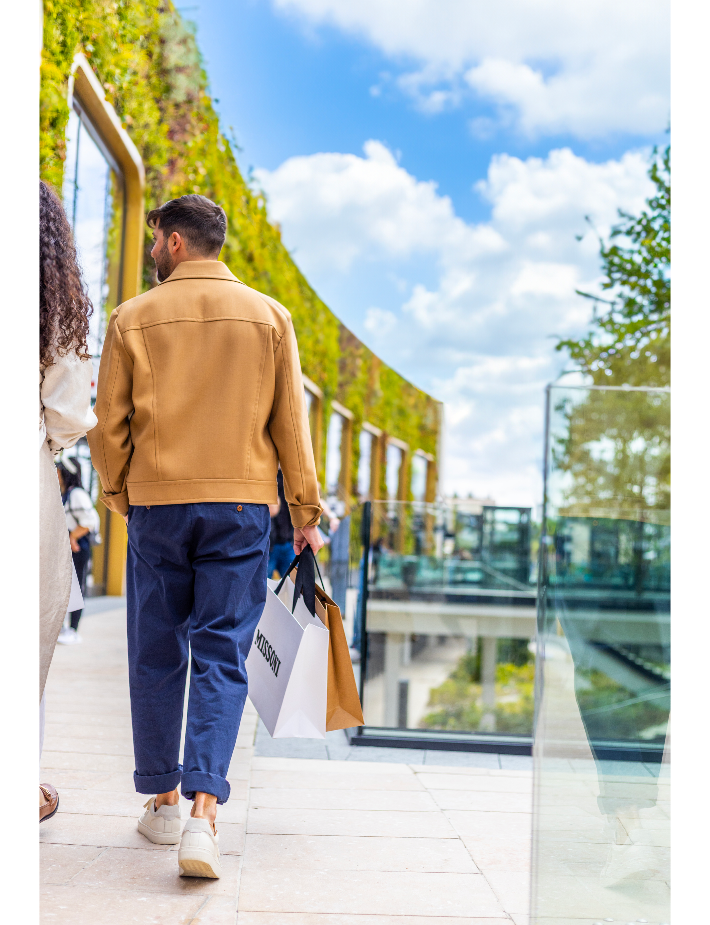 a person walking through a modern outdoor shopping area at McAthurGlen
