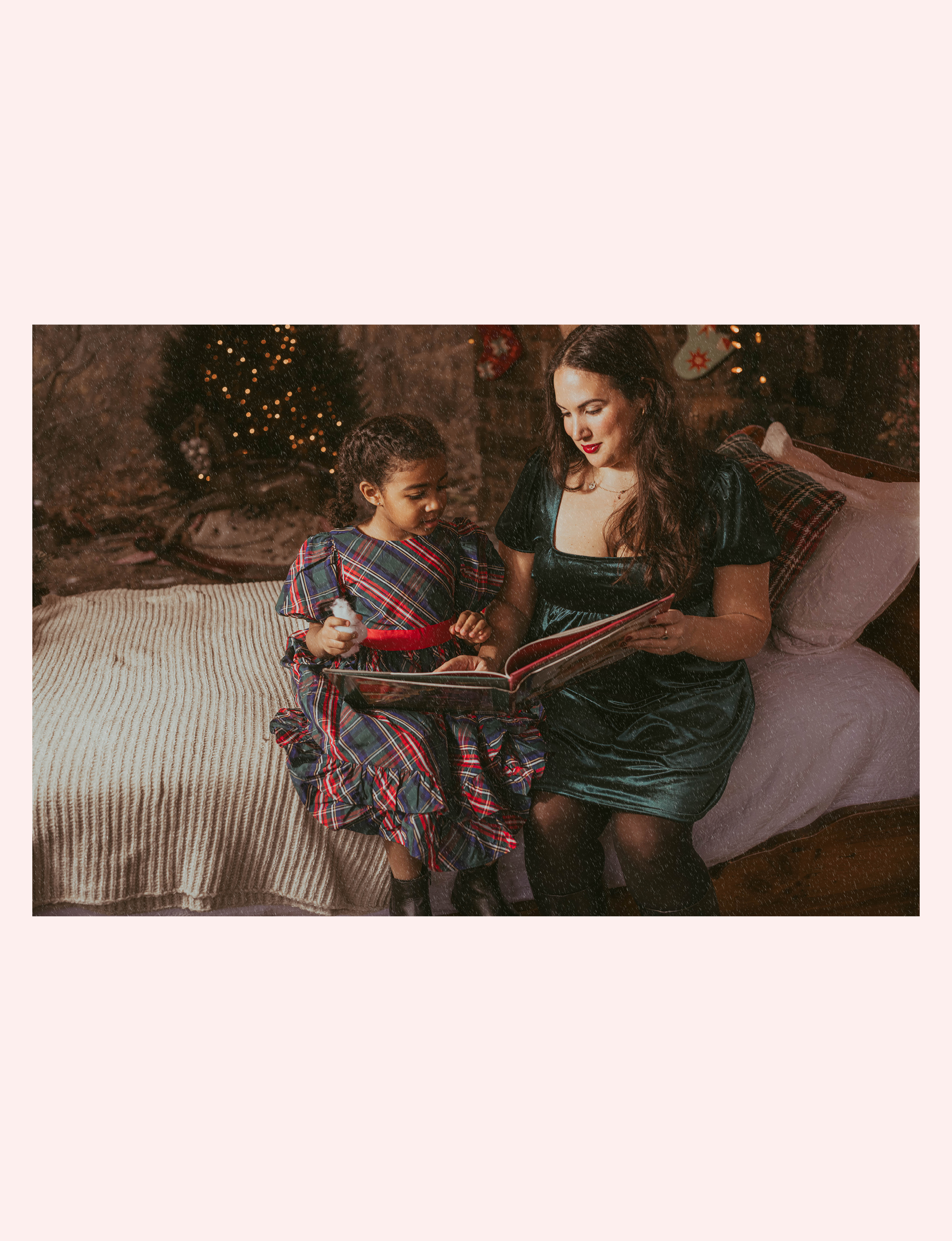 Mother and daughter reading book with Christmas tree