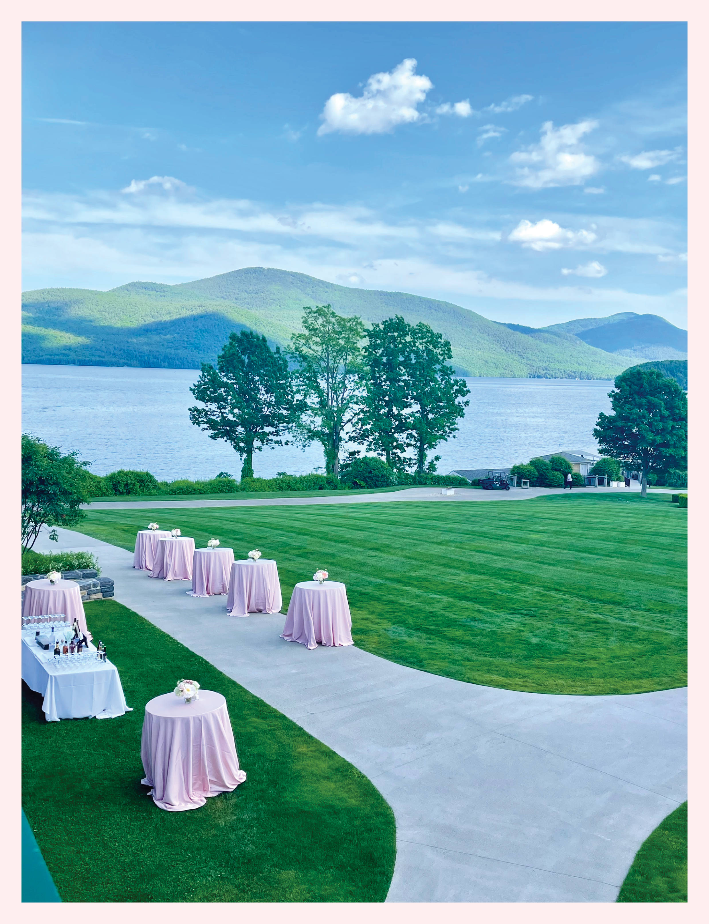 an outdoor event setup with pink-draped cocktail tables on a manicured lawn overlooking Lake George at The Sagamore Resort in Bolton Landing, New York