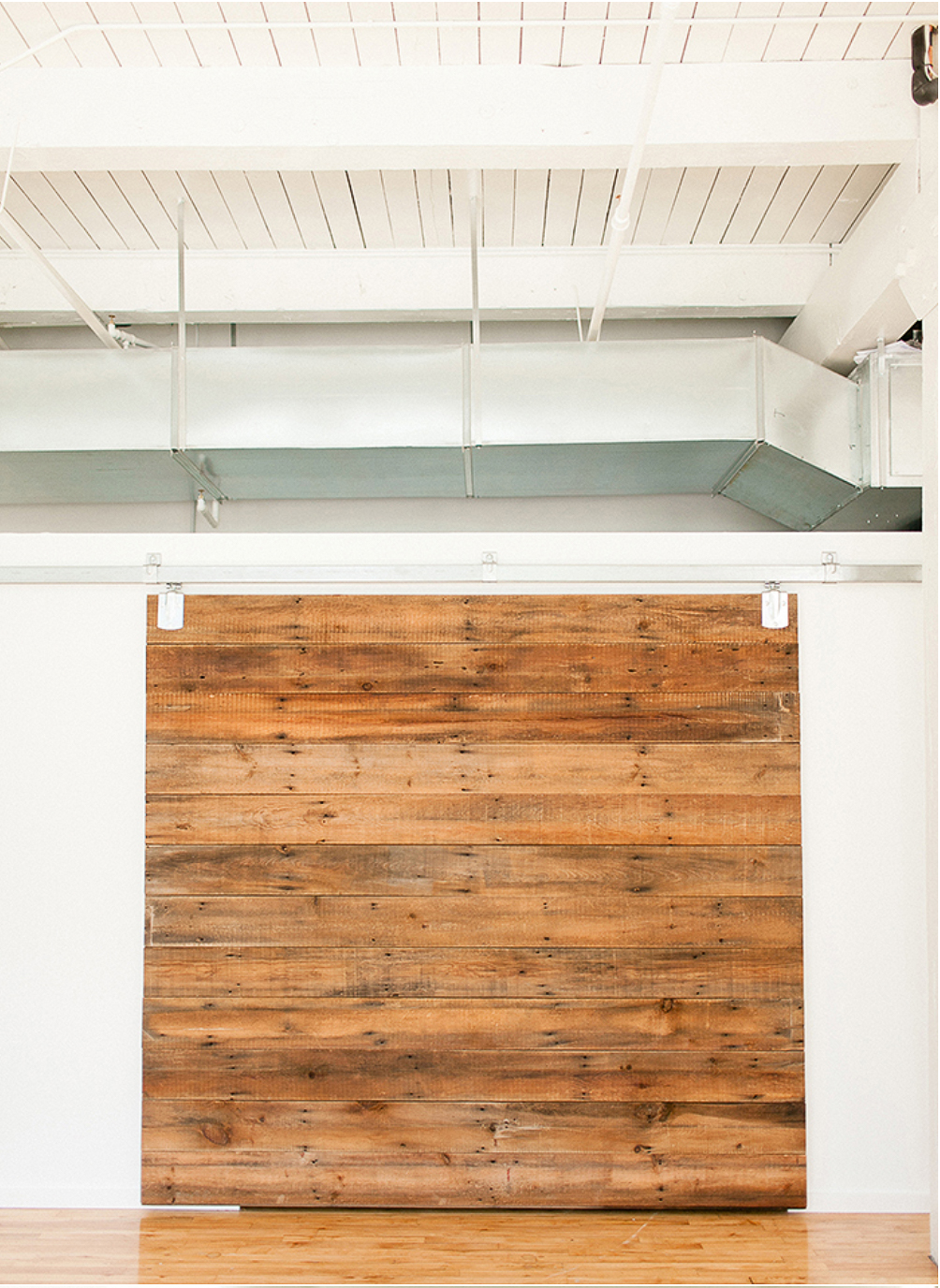 Custom-made sliding barn door reveals a dressing room and storage area.