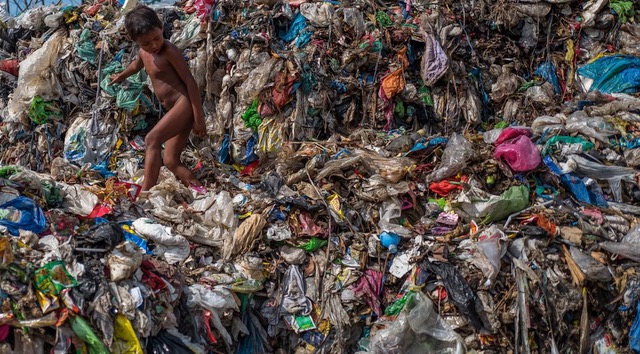 DAGUPAN, PHILIPPINES. A YOUNG BOY CLIMBS OVER PLASTIC DEBRIS IN A 50-YEAR-OLD DUMP OVERLOOKING THE OCEAN IN THIS SEASIDE TOWN. MOST OF THE BIODEGRADABLE ITEMS HAVE LONG SINCE ROTTED, LEAVING A MOUNTAIN OF MULTICOLORED PLASTICS THAT FLOAT OUT TO SEA ON THE COASTAL WINDS.