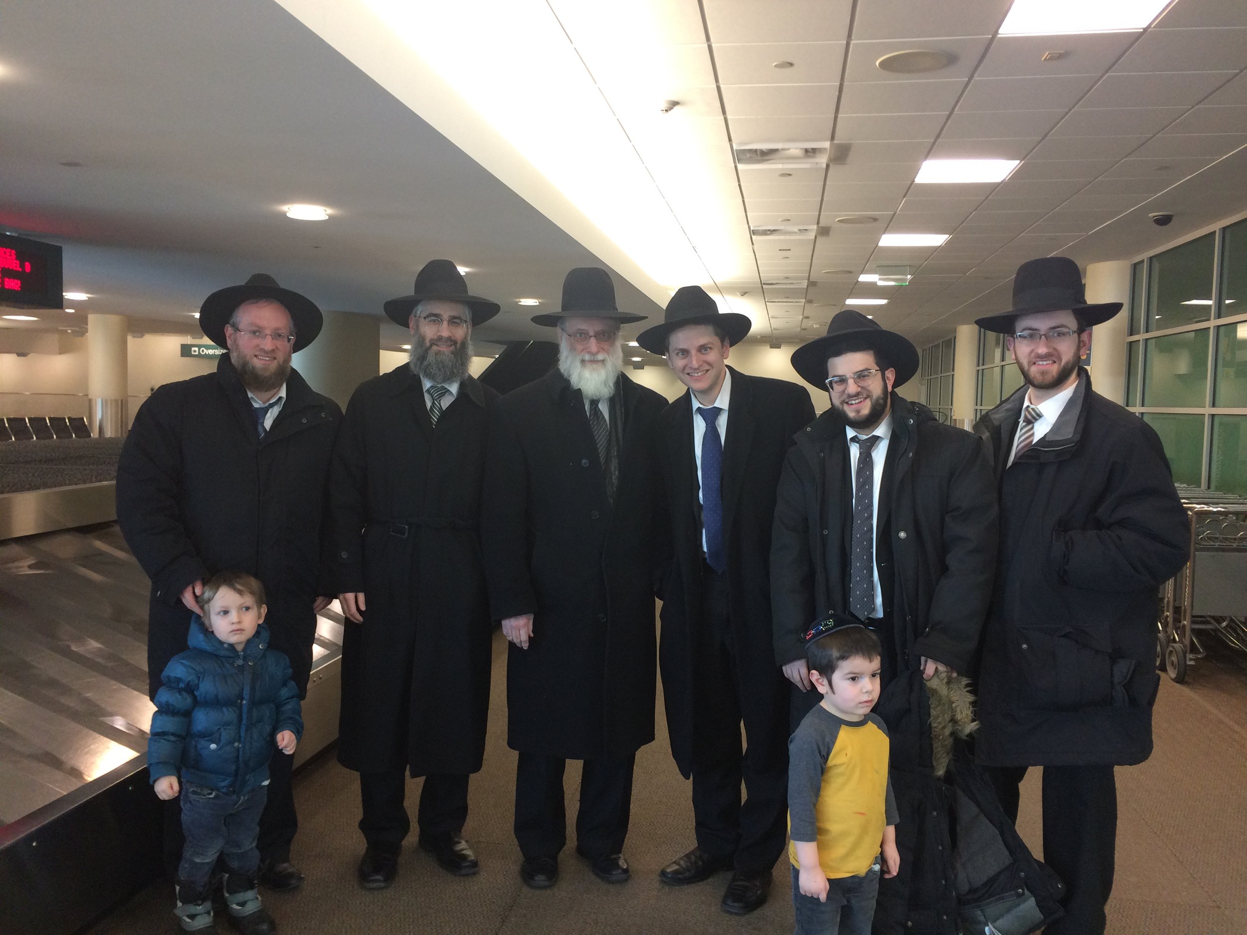 Welcoming the Birons at MSP Airport From Left: Rabbi Yossi Lowinger (with Yaakov) Rabbi Yechezkel Greenberg, HaRav Chaim S. Gibber, Me (with Elya), Rabbi Adam Crystal