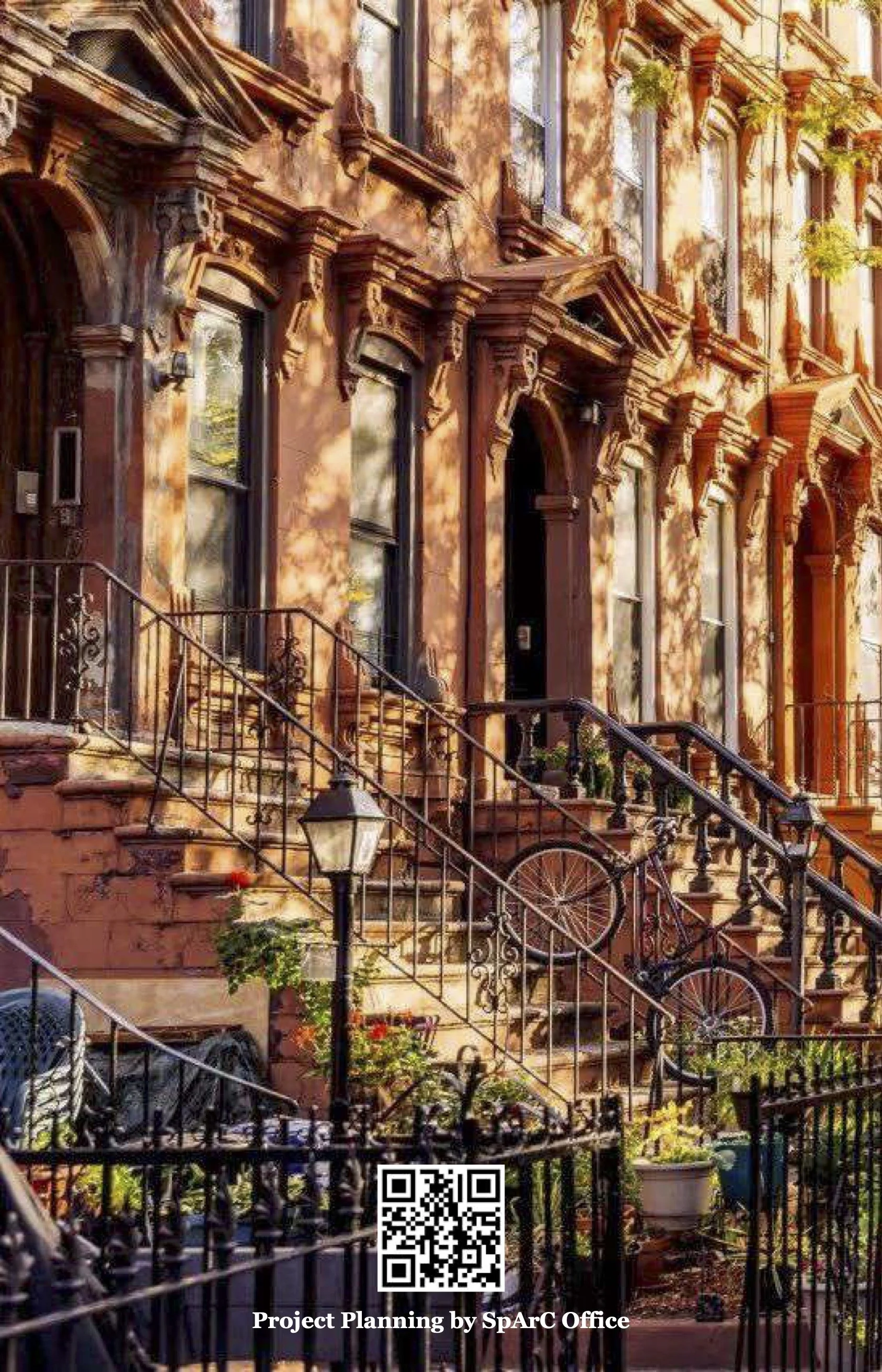 Brownstone townhouse with steps leading up to black doors, iron railings, and decorative window moldings, surrounded by outdoor plants and a street lamp.