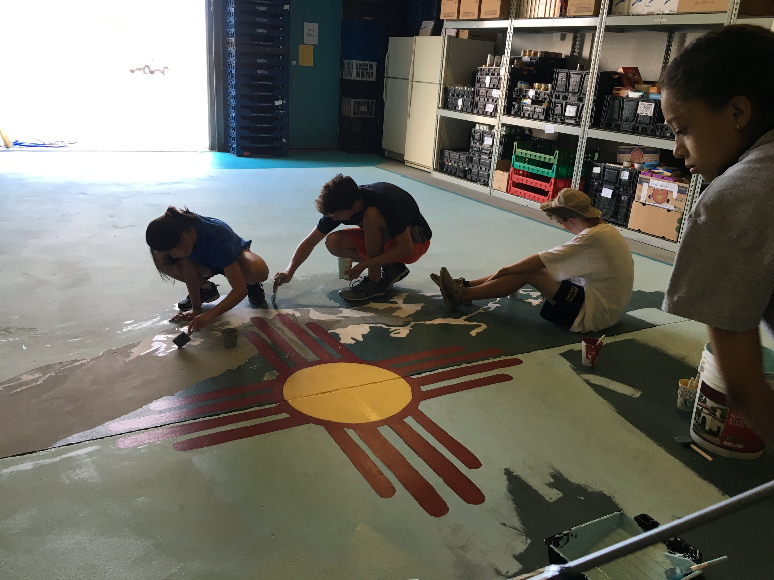 As part of Young Episcopalians in Service Colorado's service trip to Albuquerque, St Barnabas Youth painted the floor of Silver Horizons Senior Food Bank with the emblem of New Mexico and the Sandias Mountains.