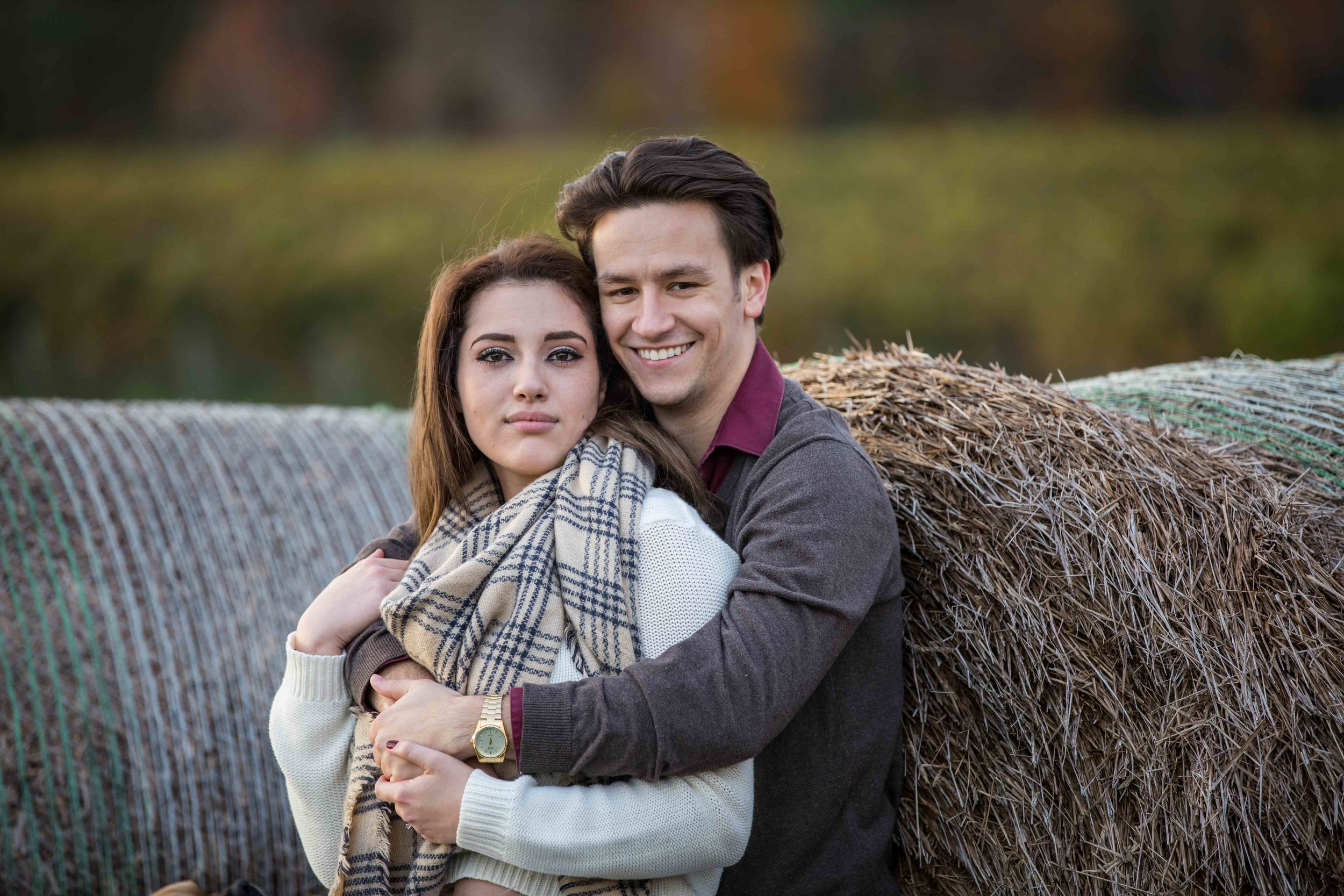  couple leaning on hay bale  