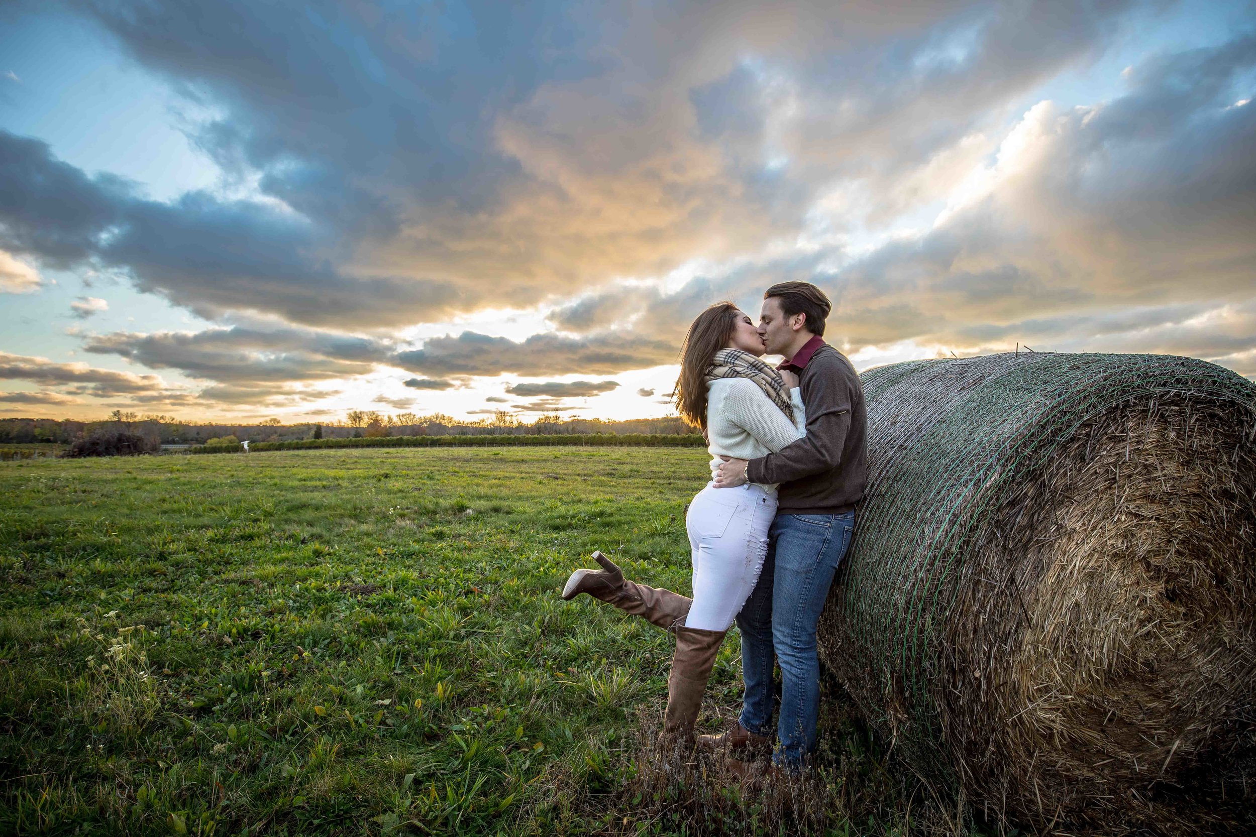  Leaning on hay bale with a leg kick kiss and a setting sun 