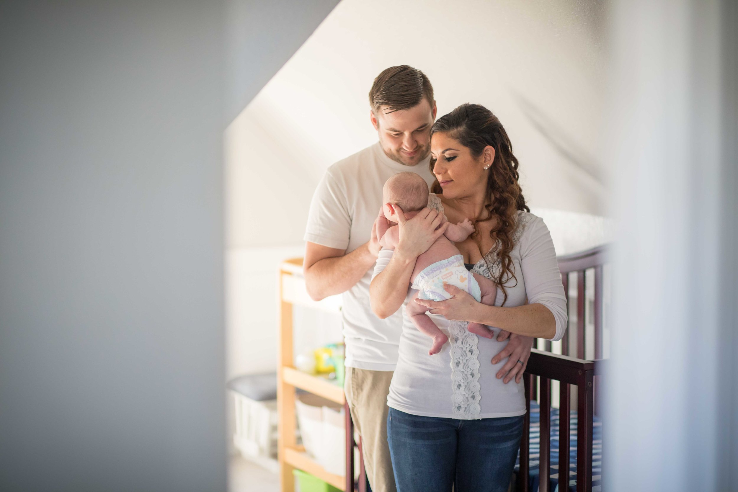  Mother and Father standing in nursery holding their infant 