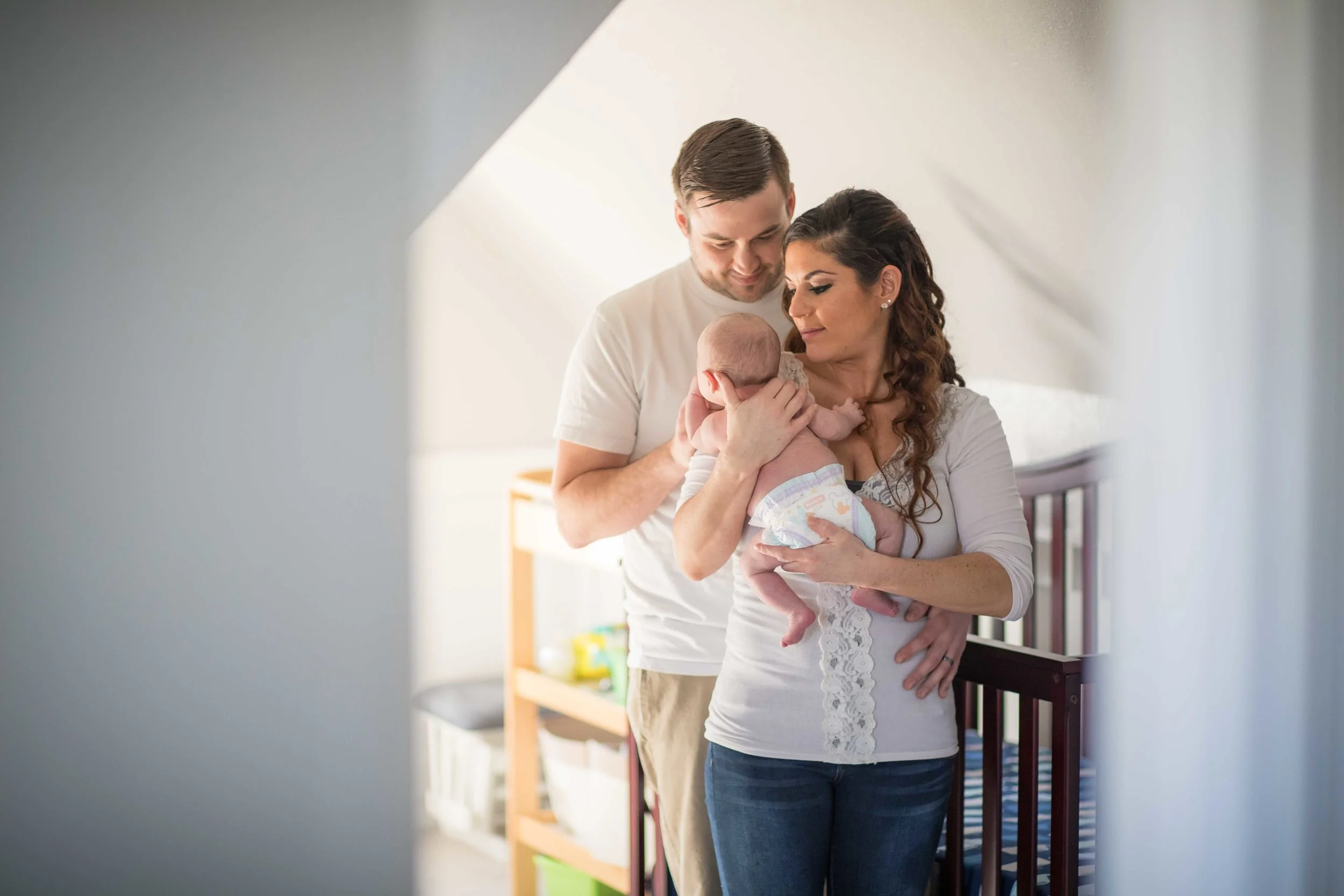 Mother and Father standing in nursery holding their infant