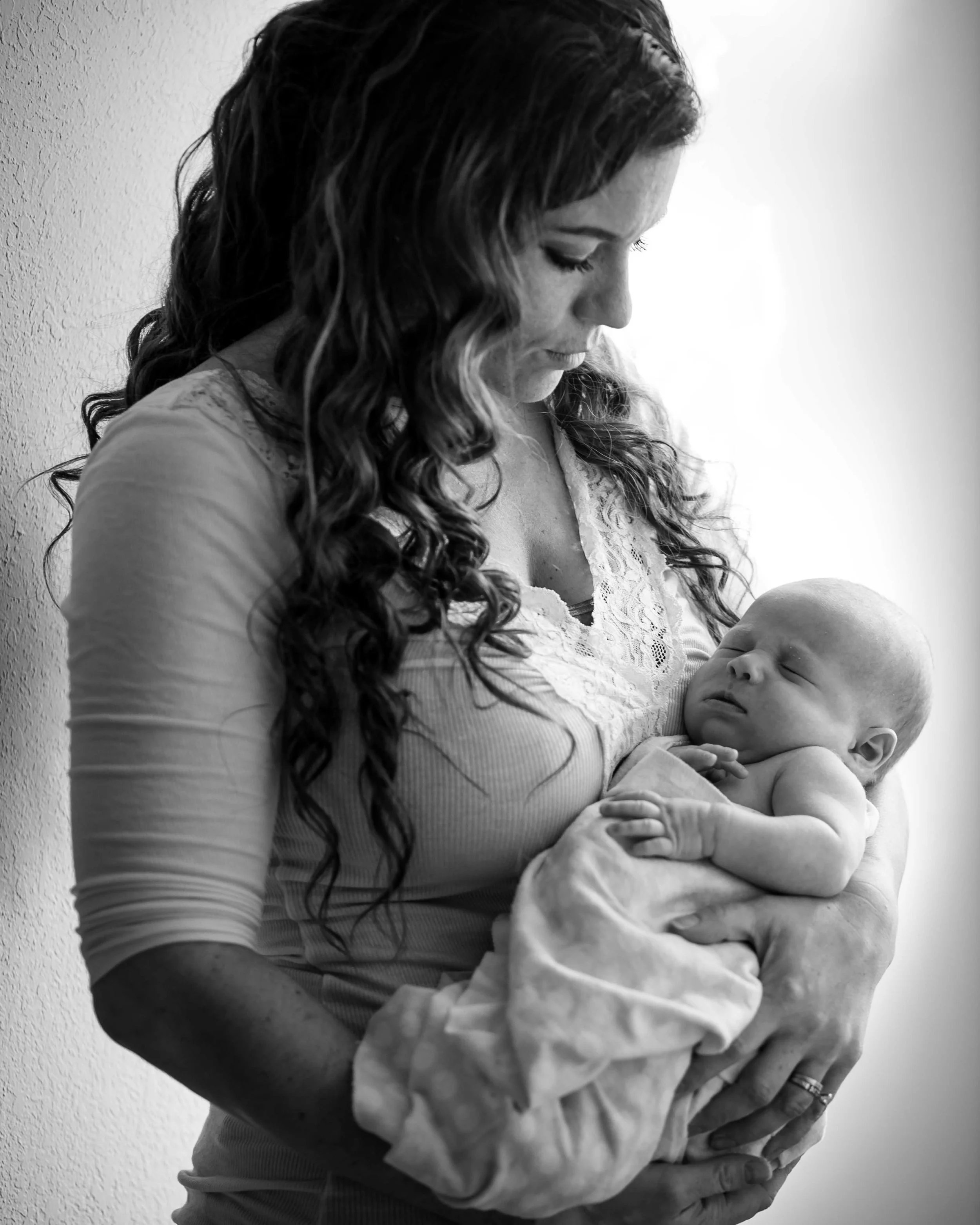 Mother holds her newborn baby boy in black and white
