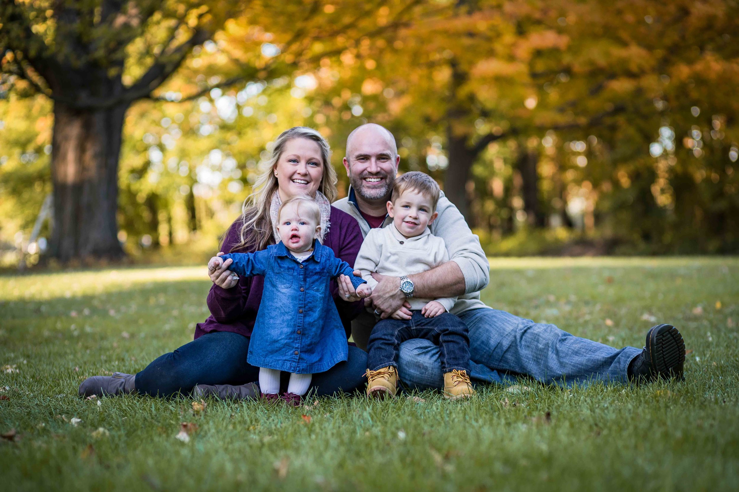  Fall Family portraits with green, yellow, and brown leaves in the background trees 