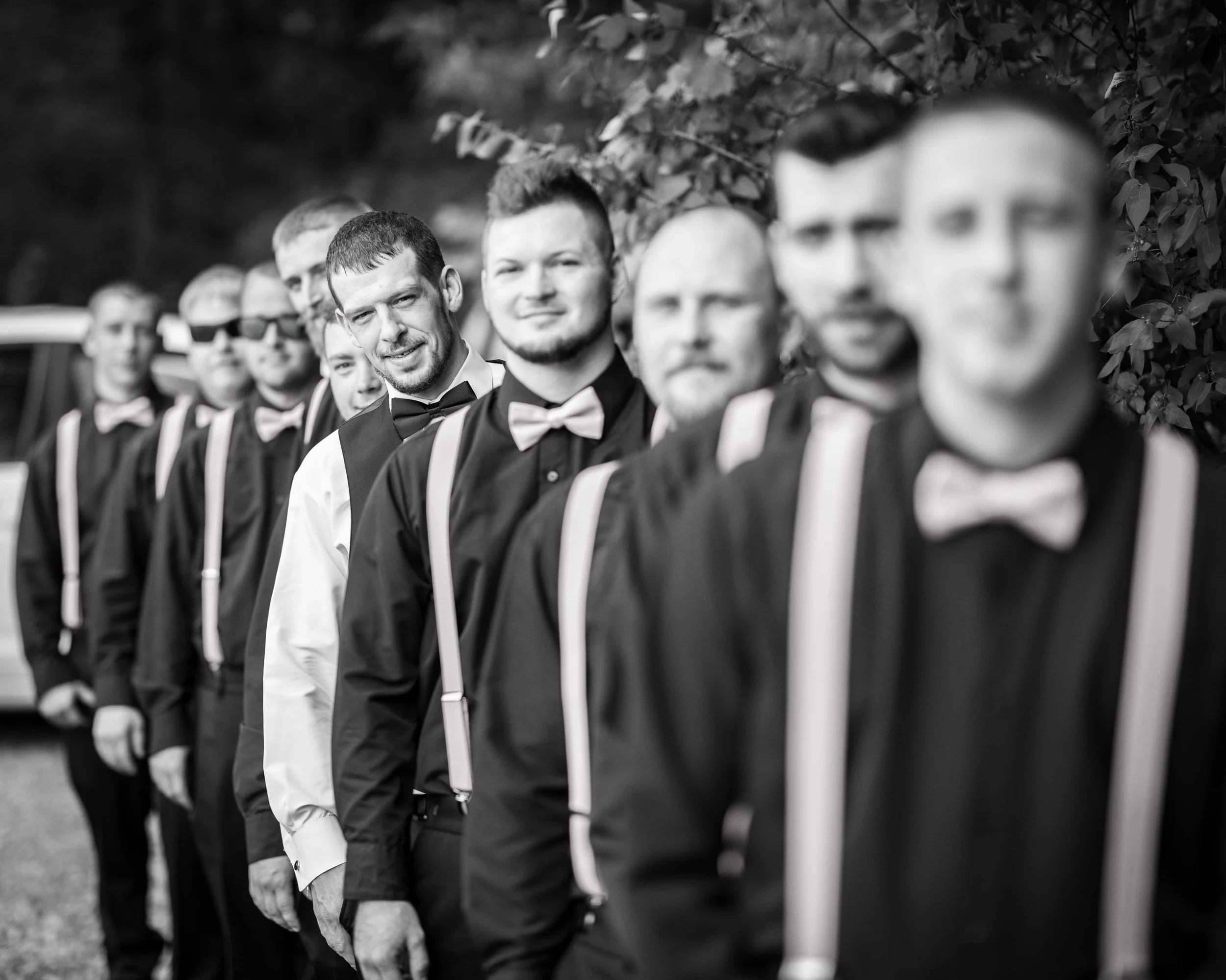 Grooms wedding party lines up for a black and white, focusing on the groom