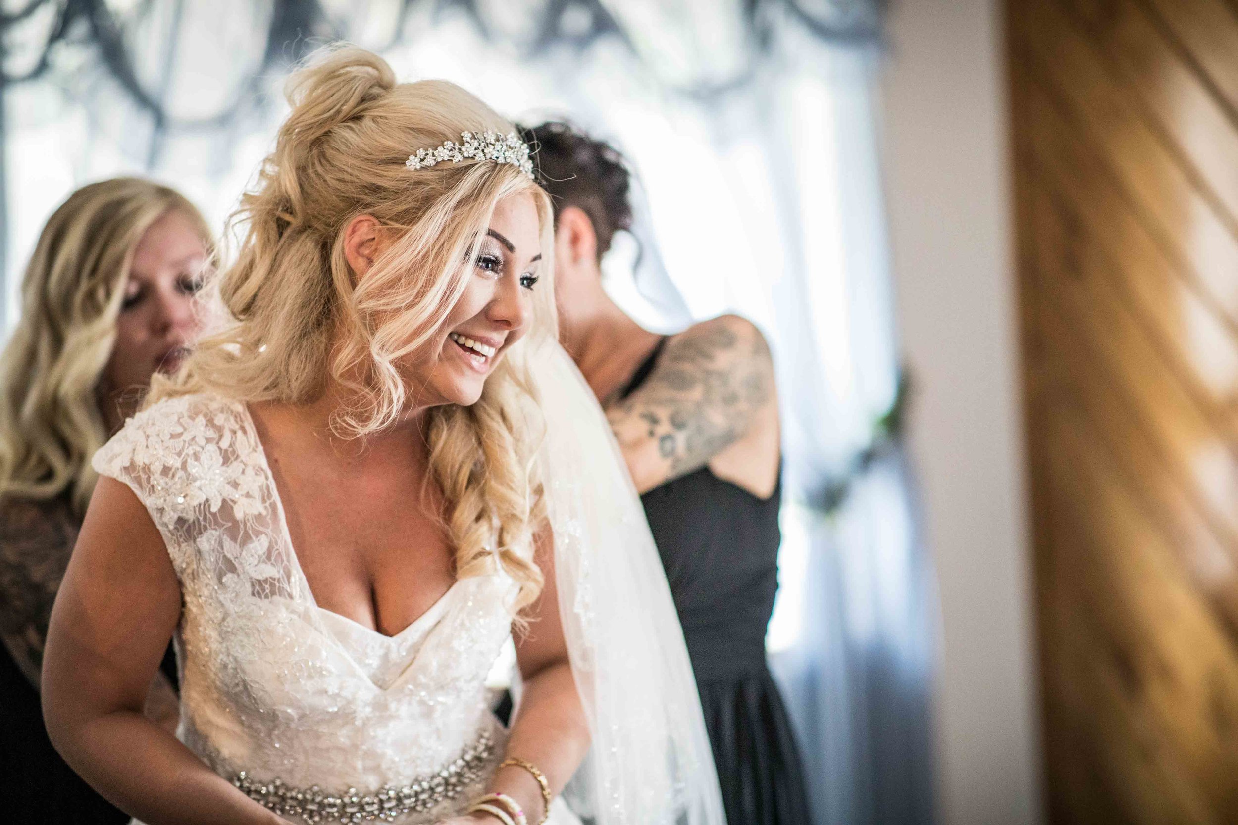  the bride laughs and cries all at the same time while her teams gets her ready 