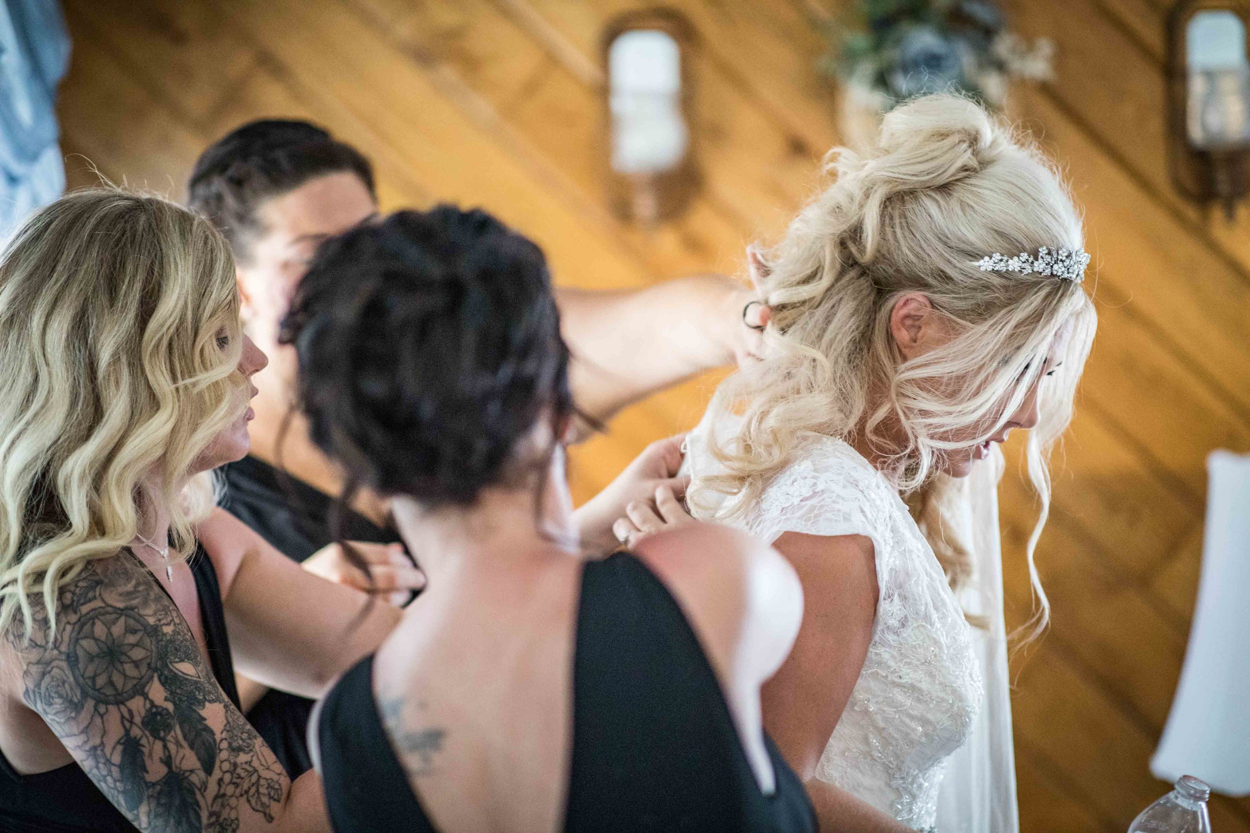  The bridesmaids frantically work together to get the bride in her dress 