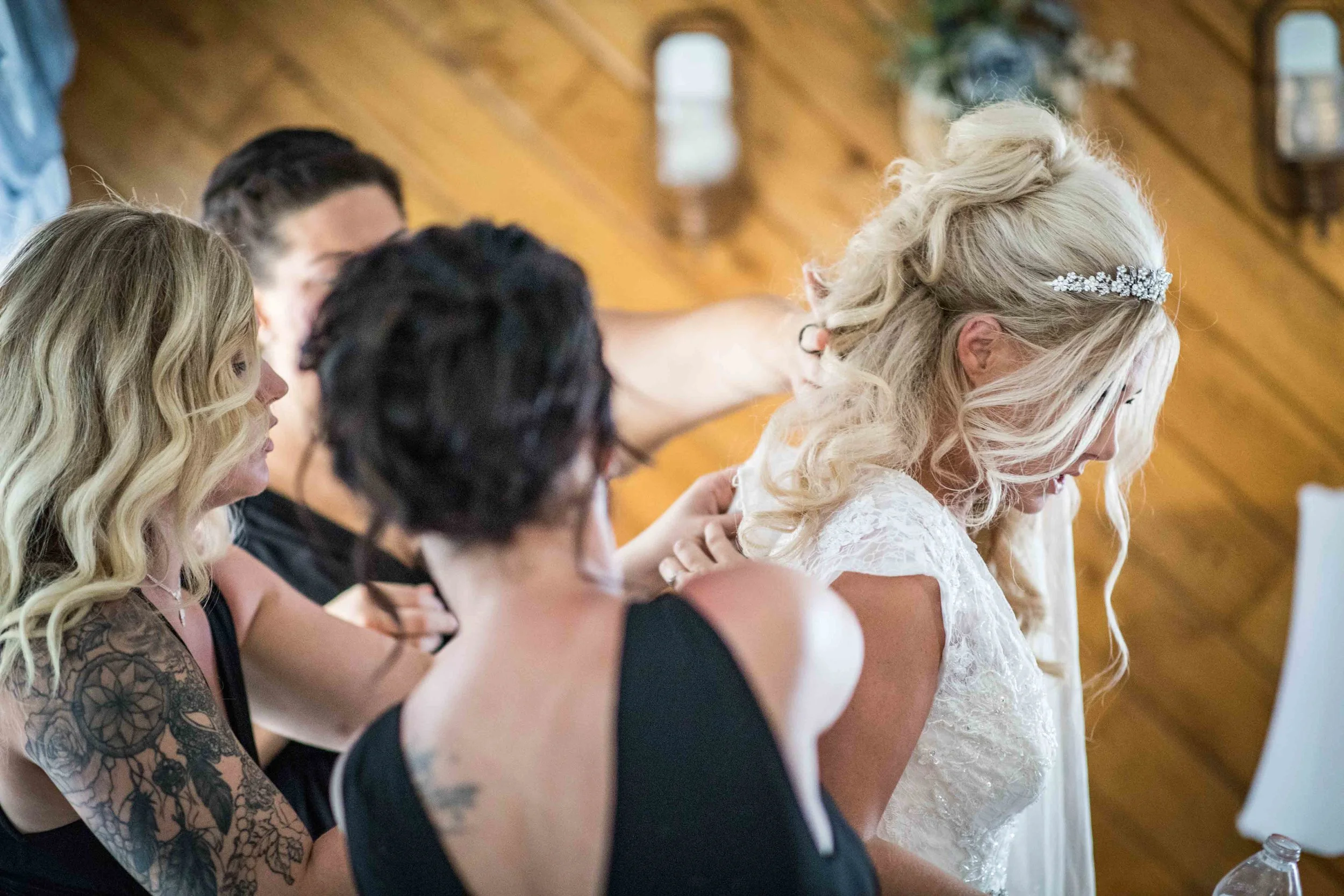 The bridesmaids frantically work together to get the bride in her dress