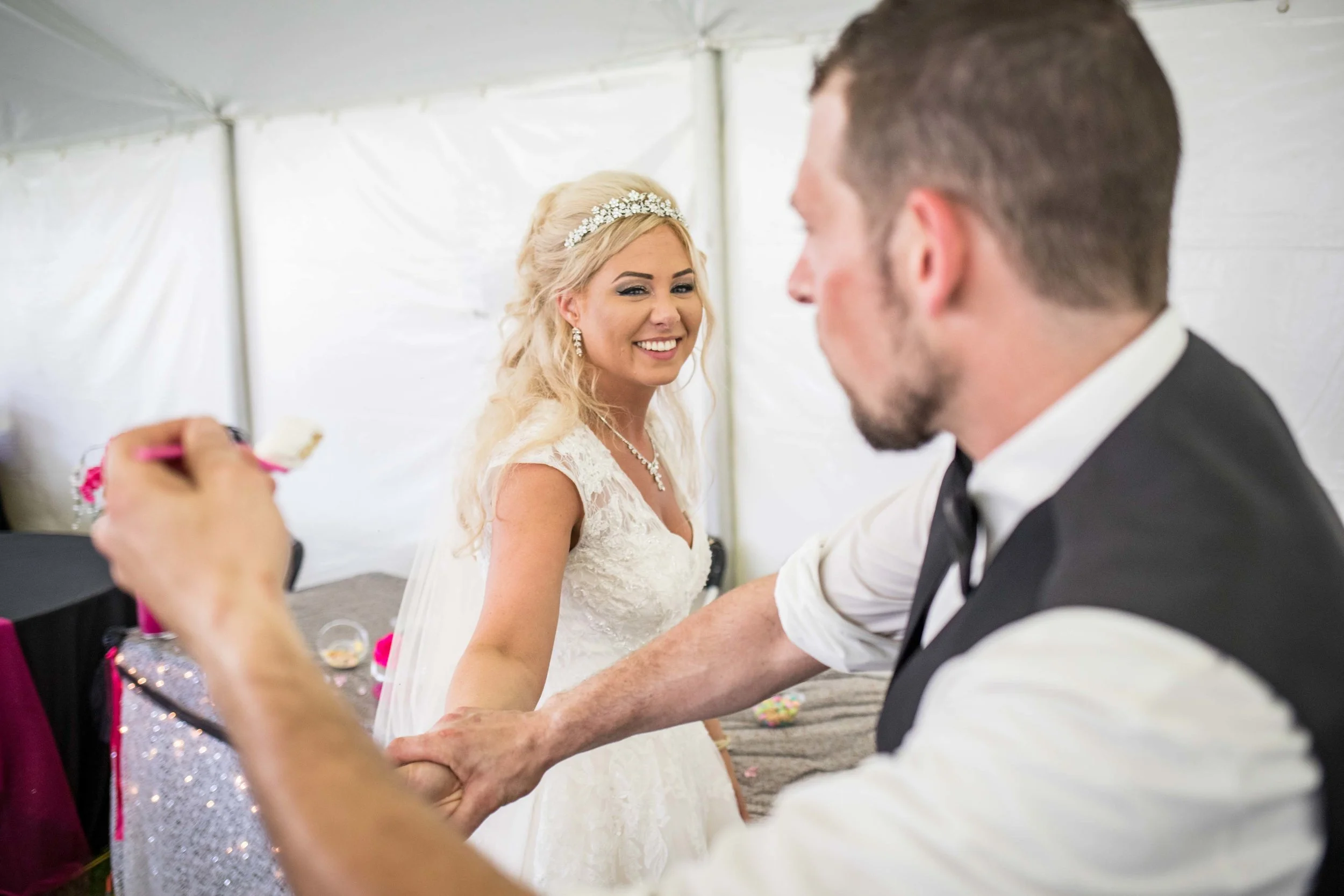 he defends himself from getting cake smashed in his face as she laughs