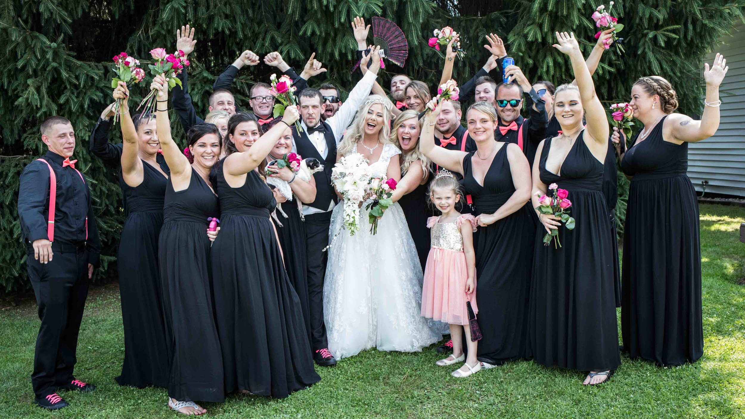  a very large wedding party celebrating with their hands in the air.  congratulating the newly weds 