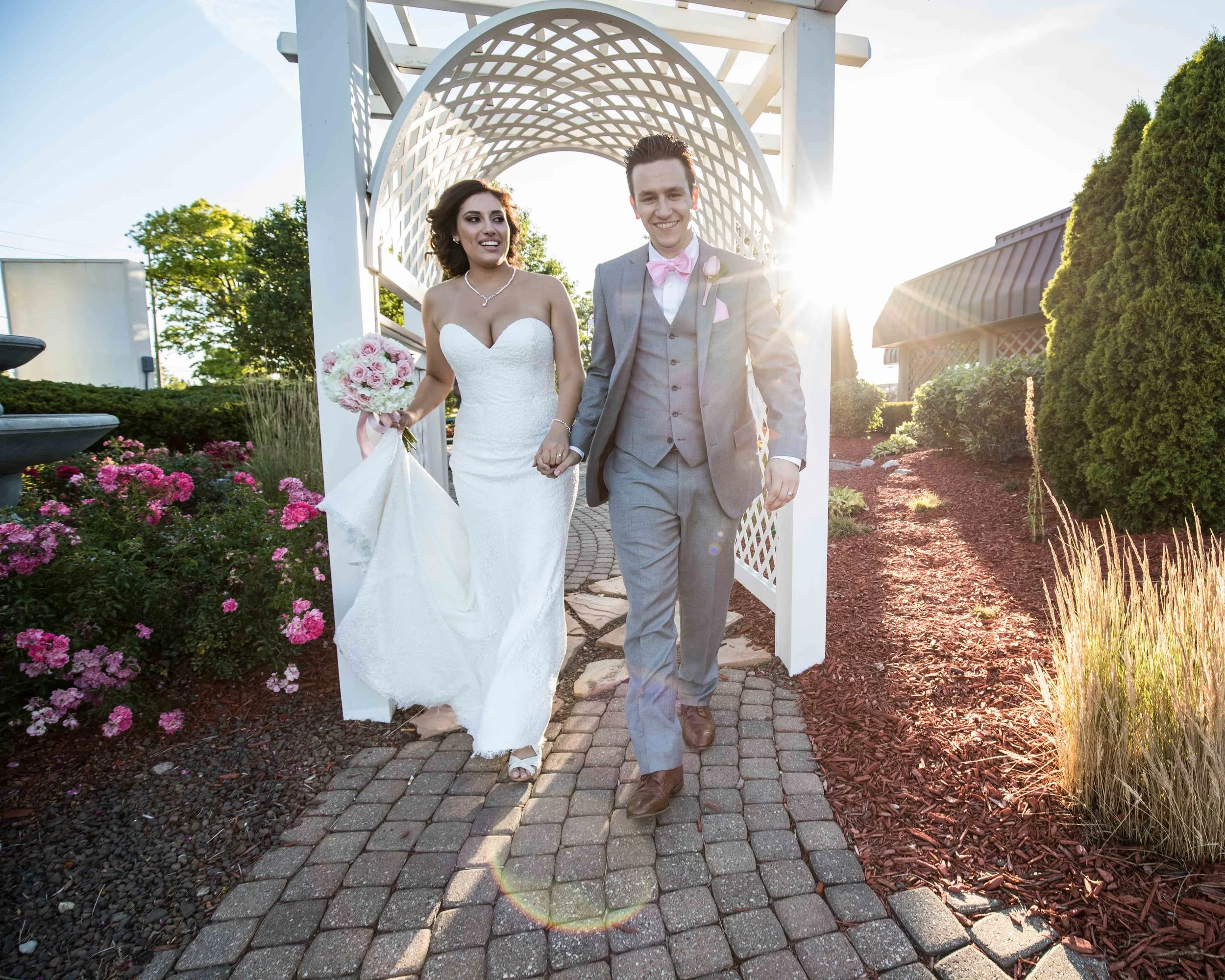 bride and groom walking through a trellis