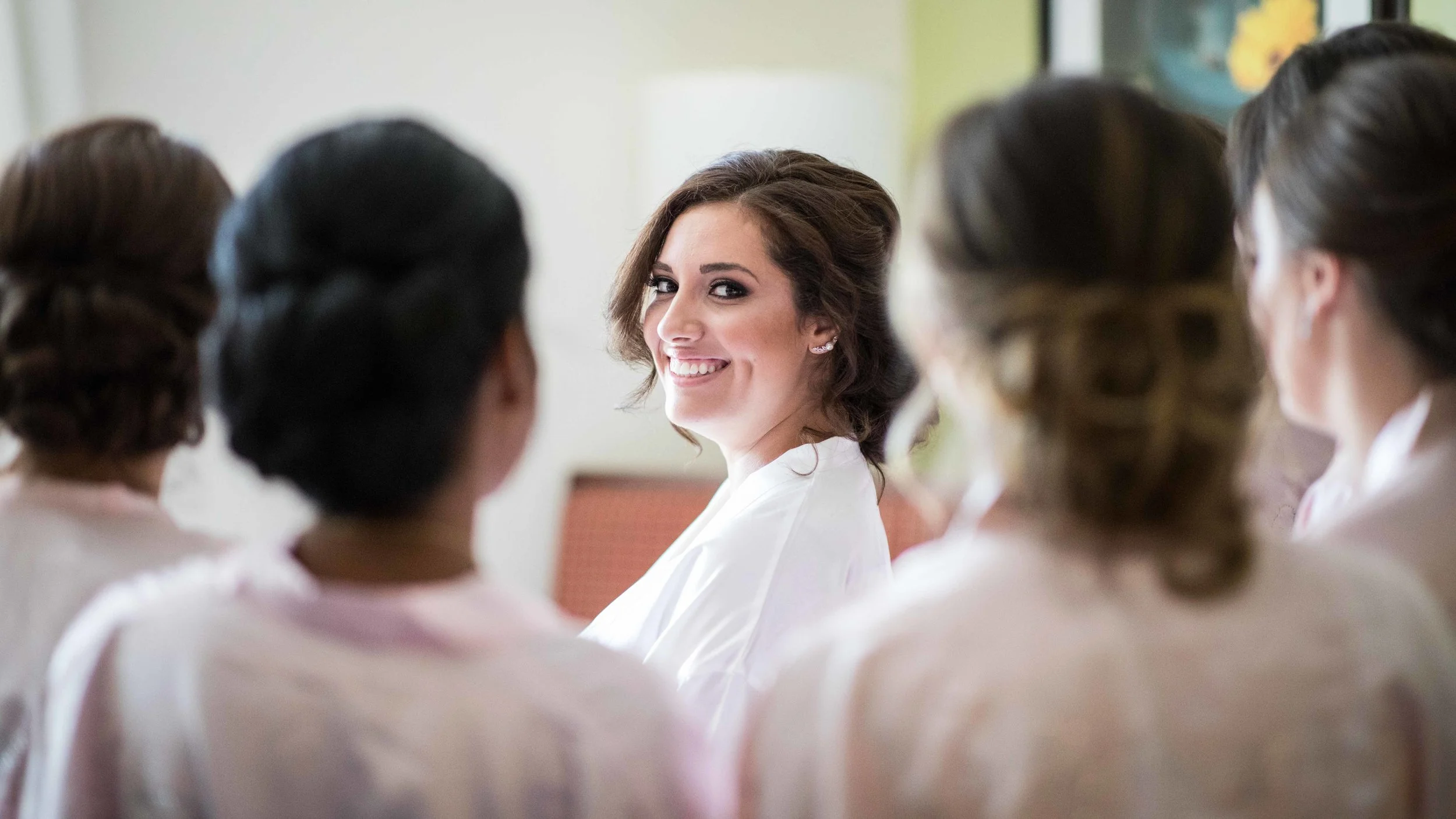 bride smiling through a circle of her bridesmaids.jpg