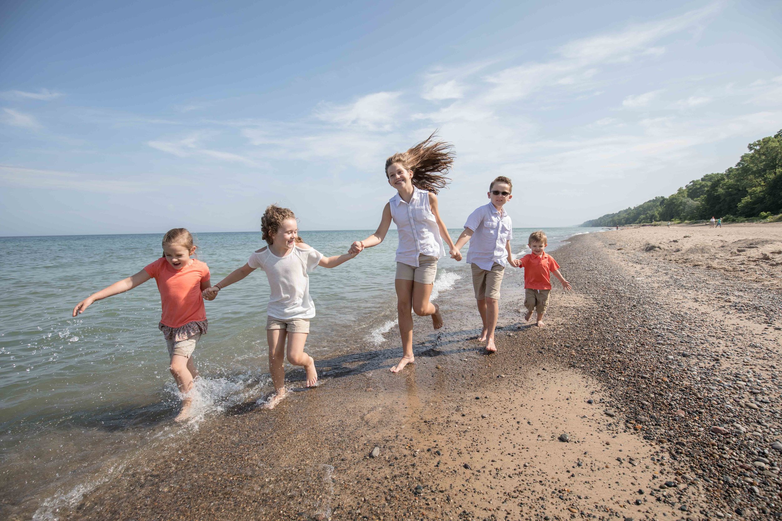  wide angel of grand children running down the beach with blue water blue skies and clean beach 