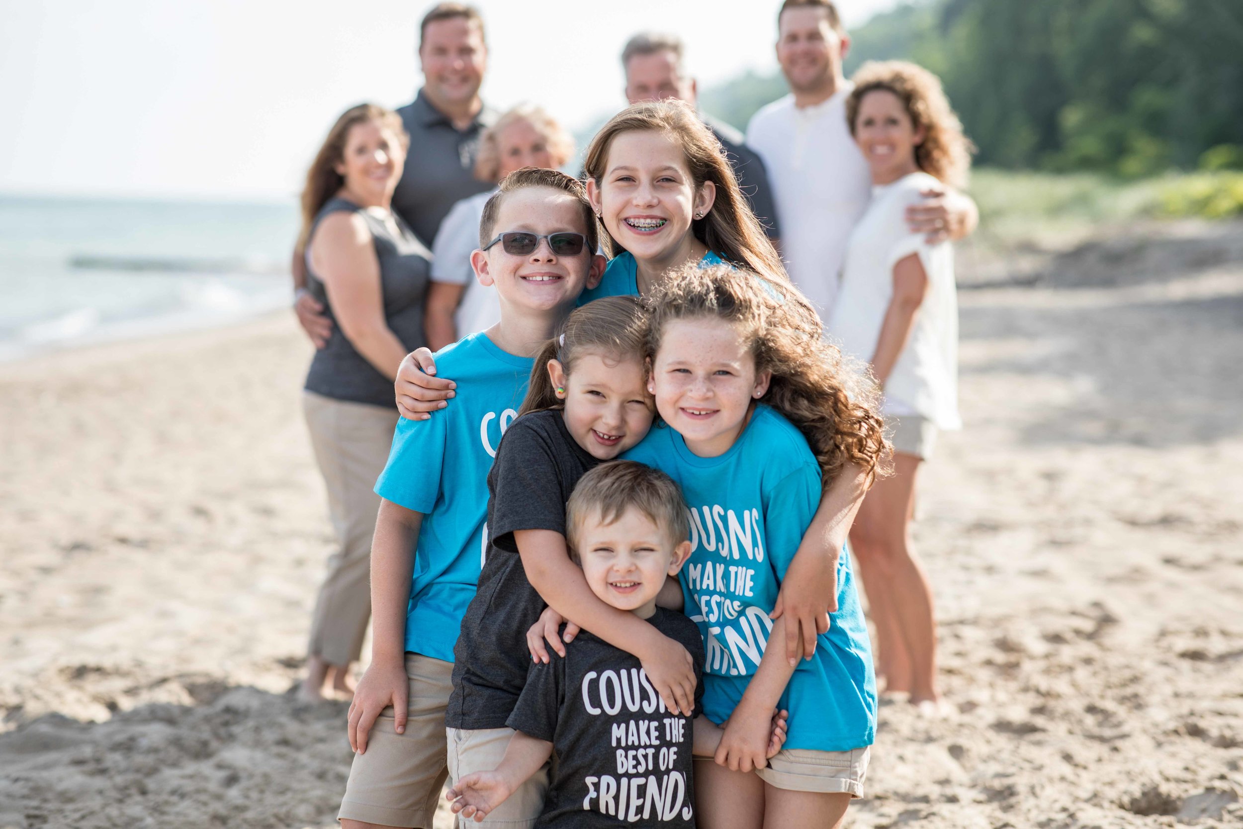  Group photo of grandchildren on the beach with parents and grand parents behind 