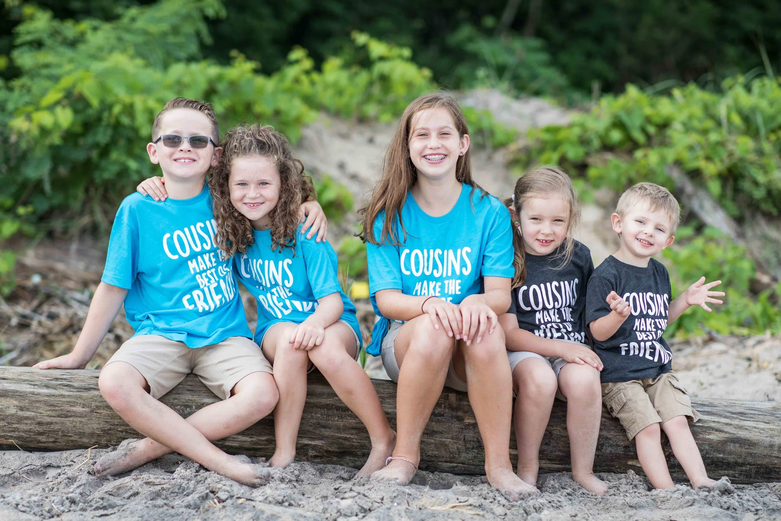 grand children posing for photo on a piece of beach driftwood