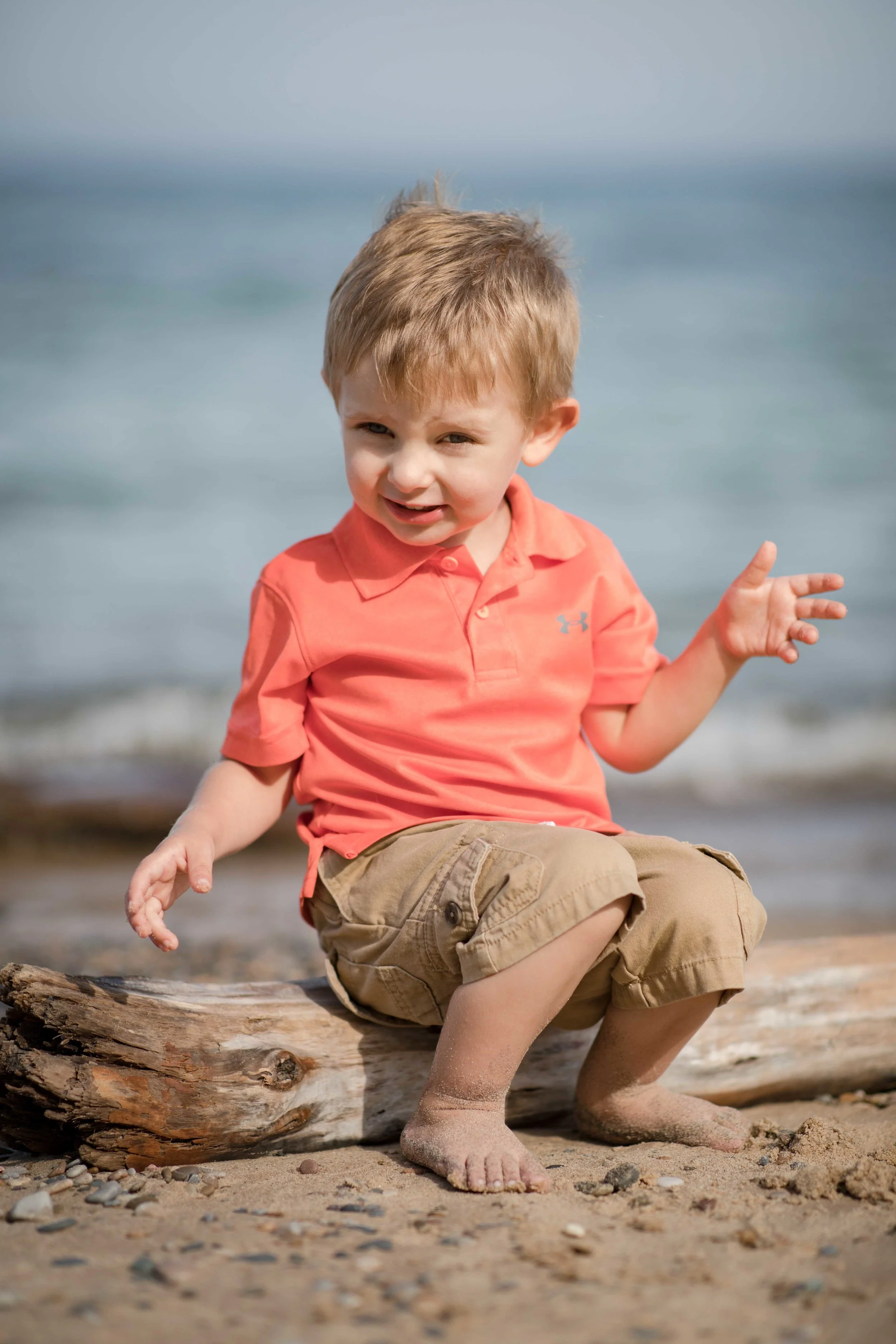 individual portrait of grand child sitting on a piece of driftwood