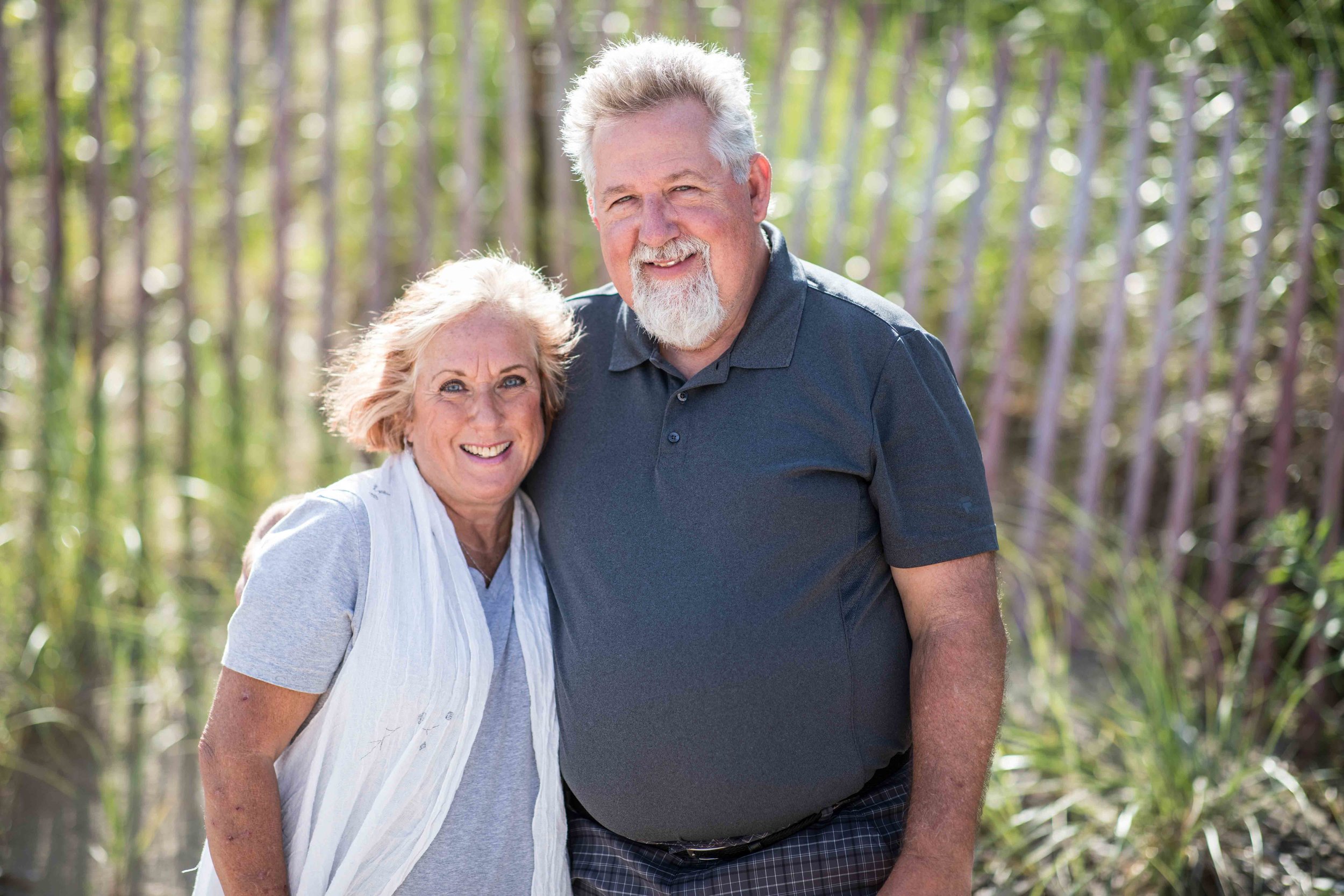  Grand parents posing in front of beach fence 