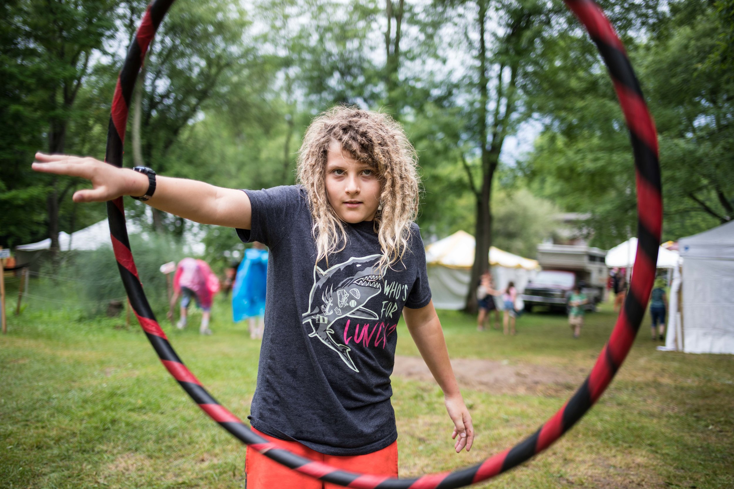  A kid facing the camera spinning a hula hoop in his arms 