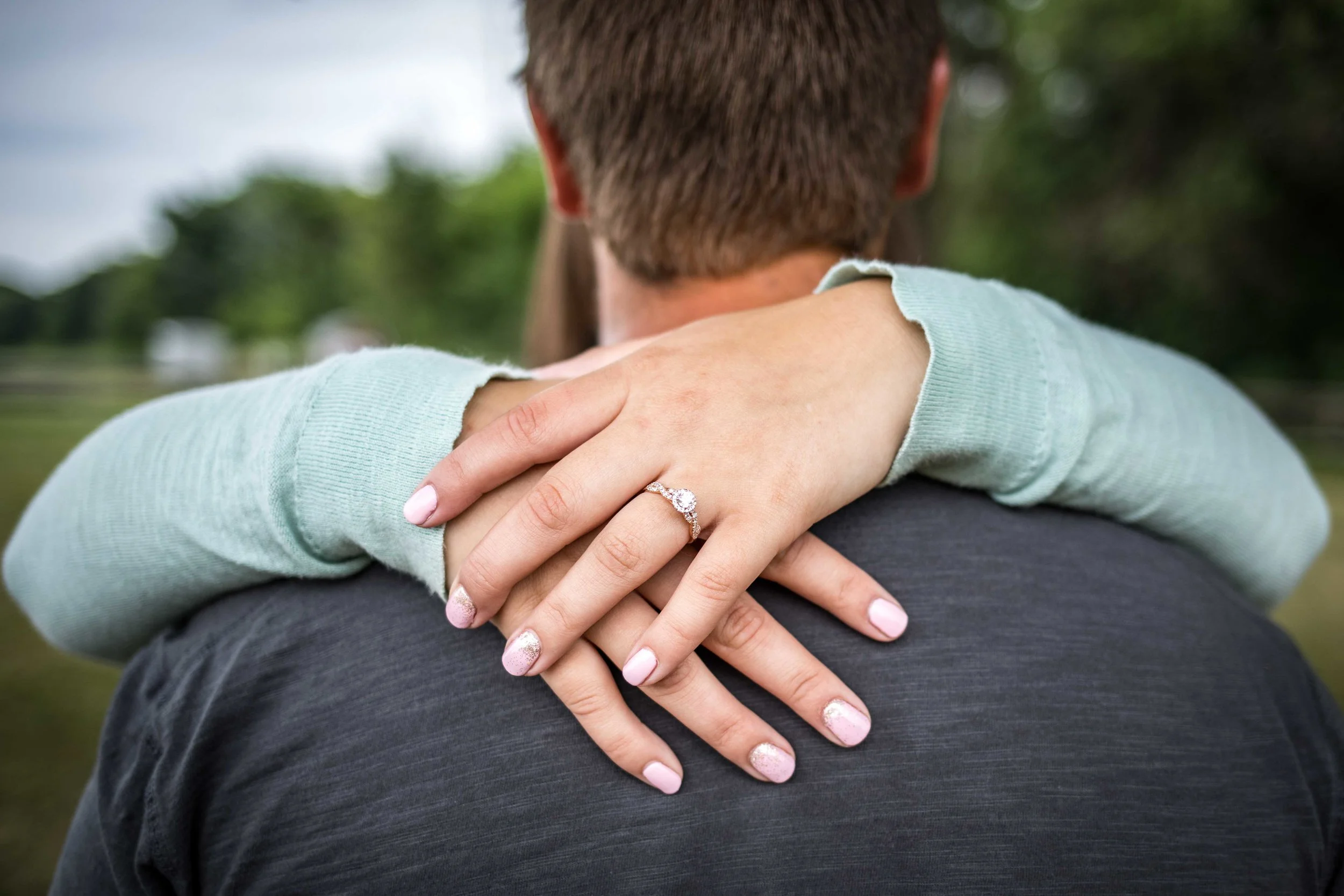 Her arms around him showing the new engagement ring