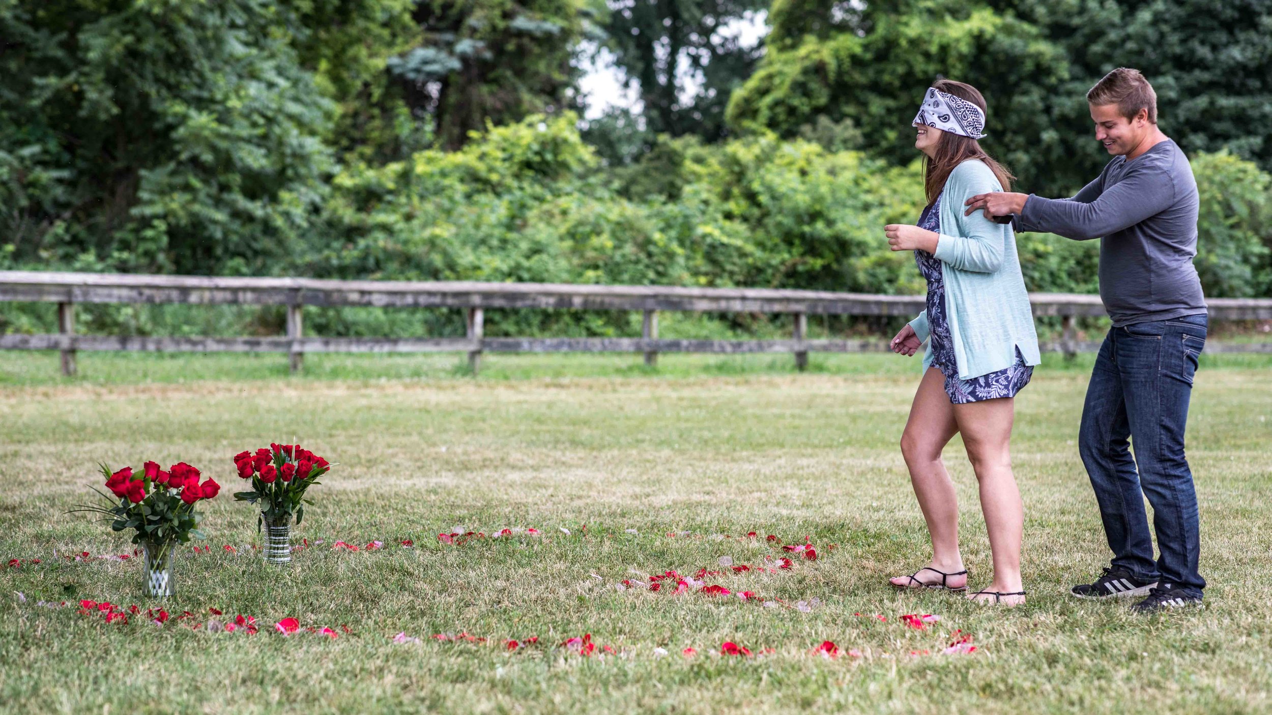  The boyfriend positions his blindfolded girlfriend in place at the top of a heart made of flower pedals 