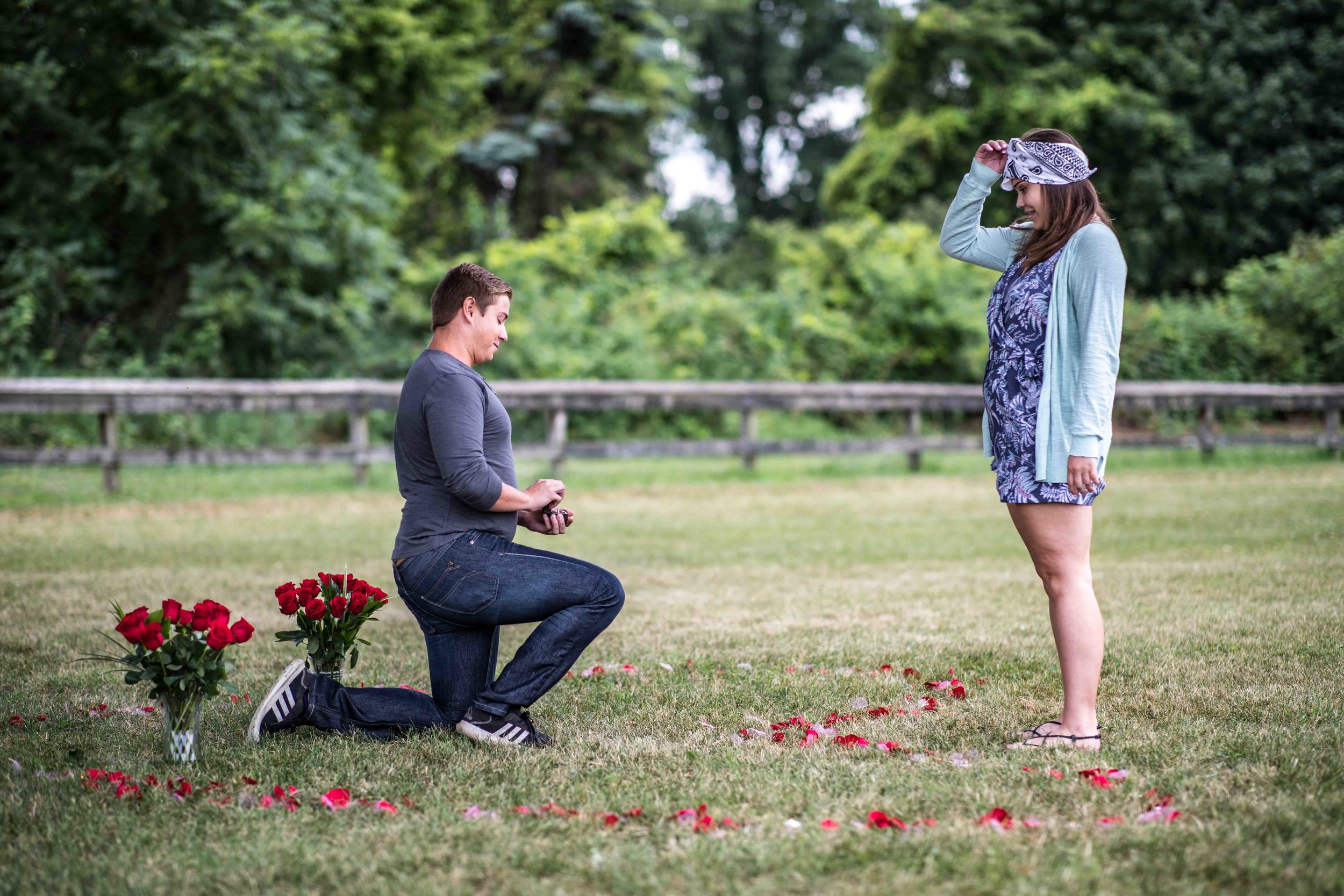  Girlfriend removes her blindfold to find her boyfriend proposing to her with flowers in the shape of a heart around them 