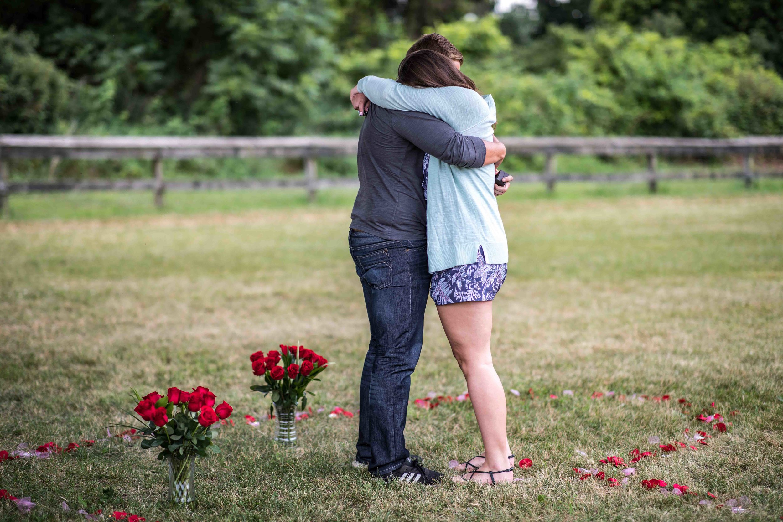  After the girlfriend says yes to his proposal they hug in the middle of a giant heart made of flower pedals on the ground around them 