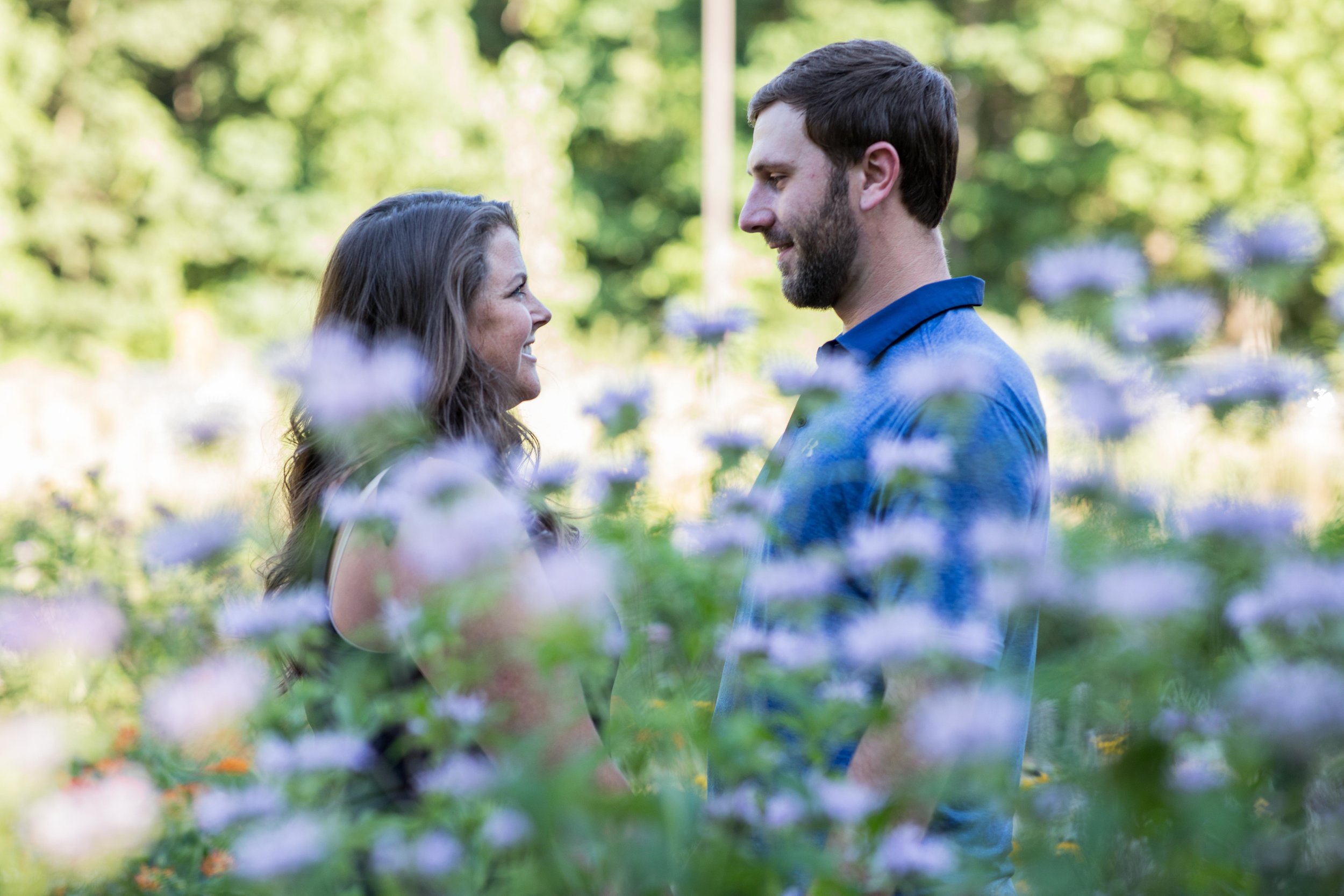  A man and woman hold hands in front of a field of wildflowers 