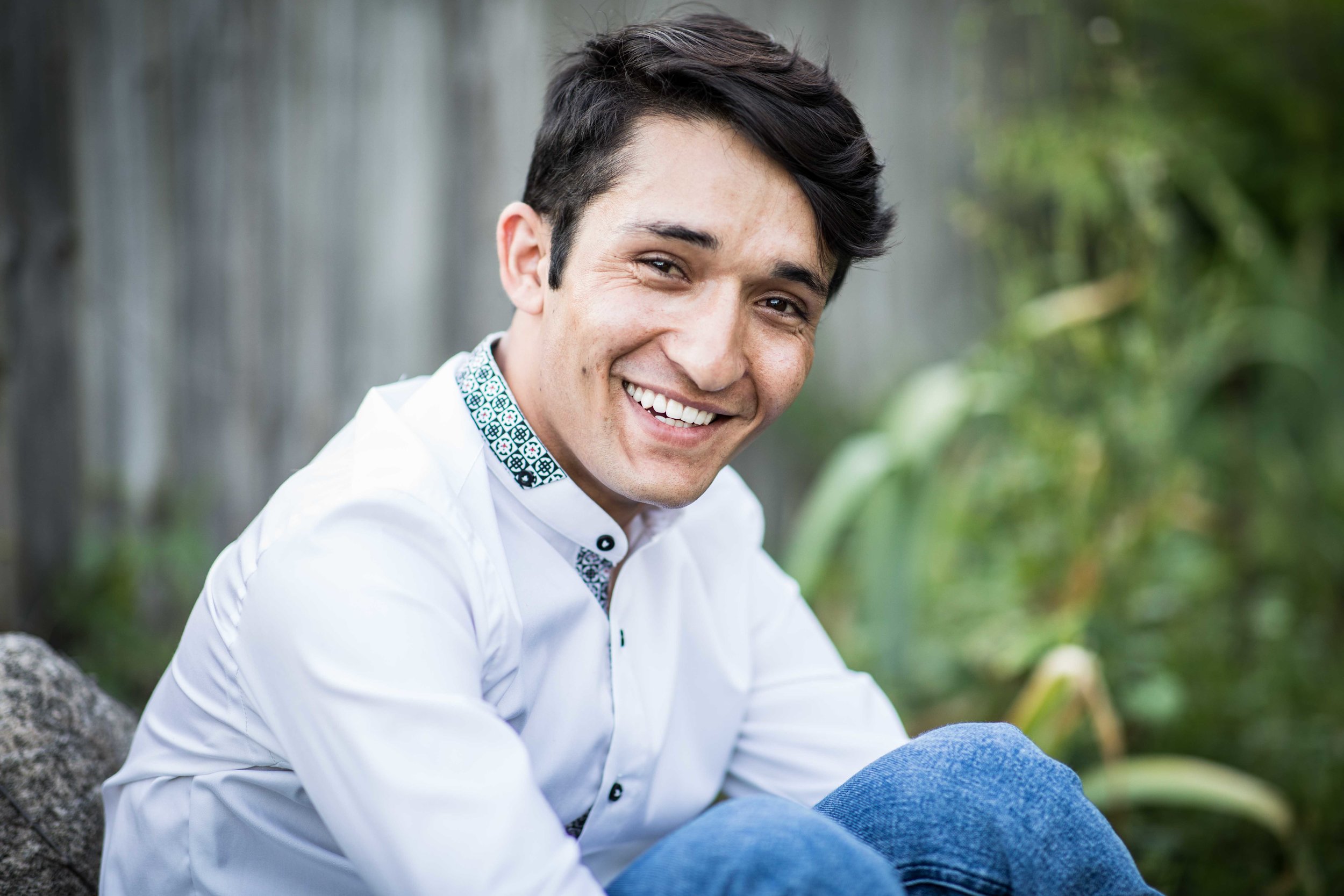  boy sitting with knees crouched smiling at camera 