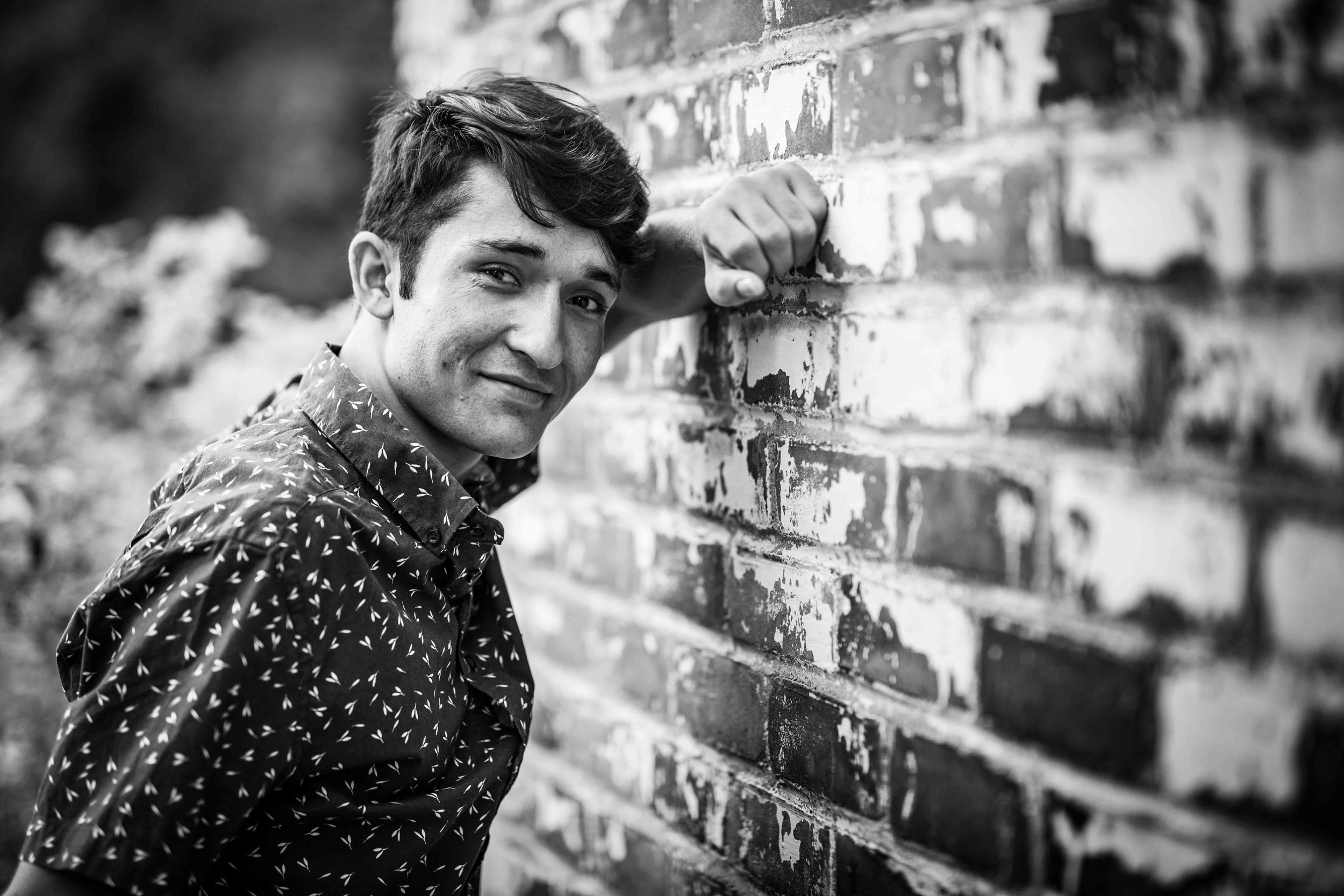  boy leaning against brick wall 