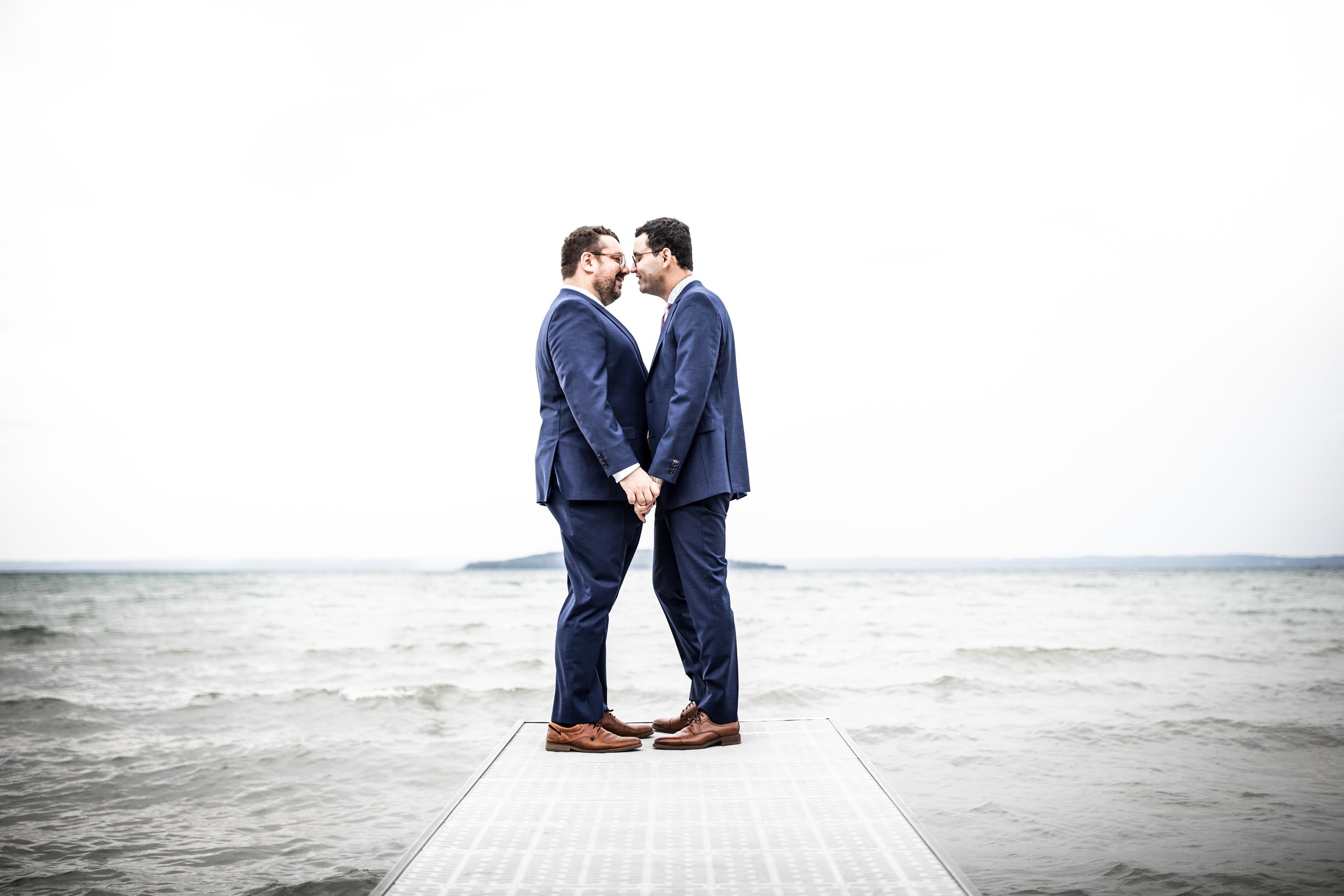  a couple holds each other at the end of a dock in front of the Grand Travers Bay 