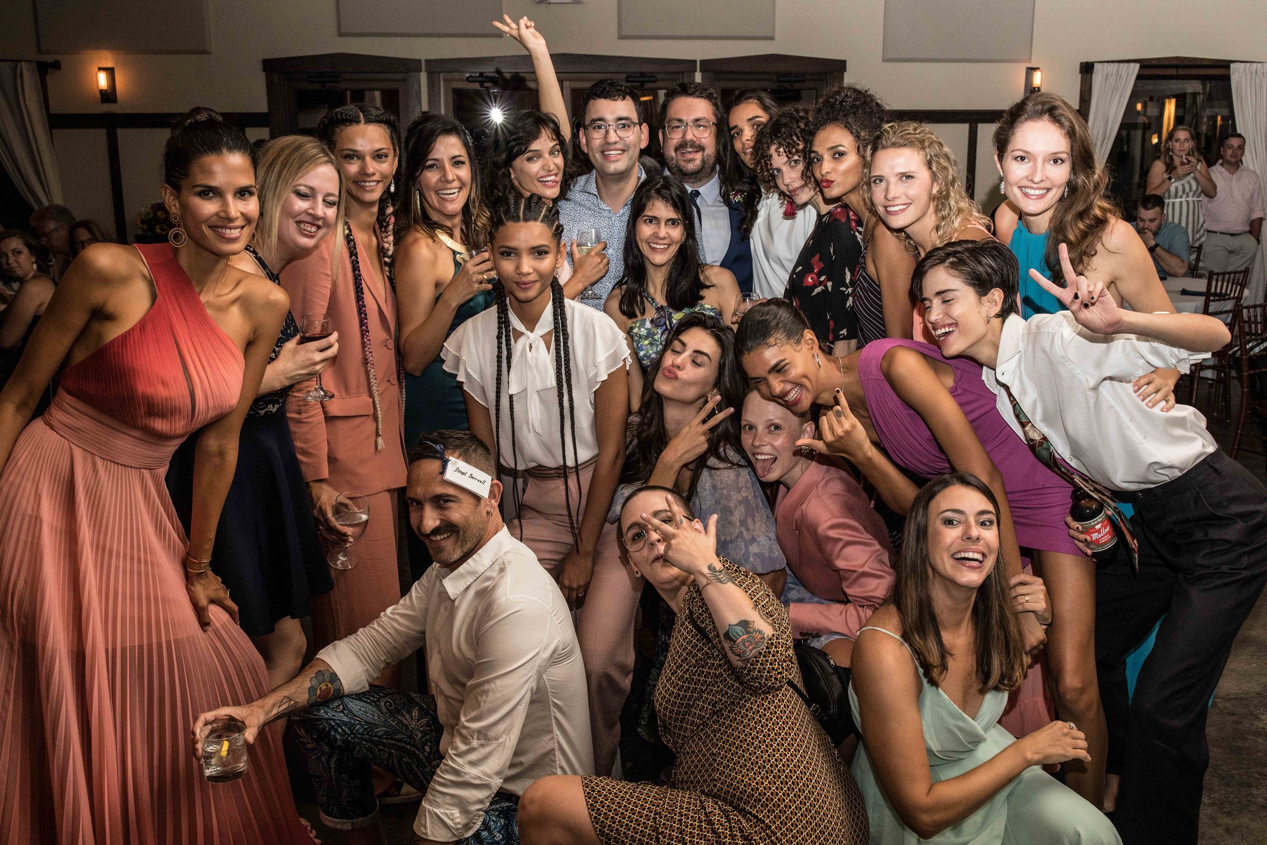  the wedding crew poses for a group photo on the dance floor of the reception 