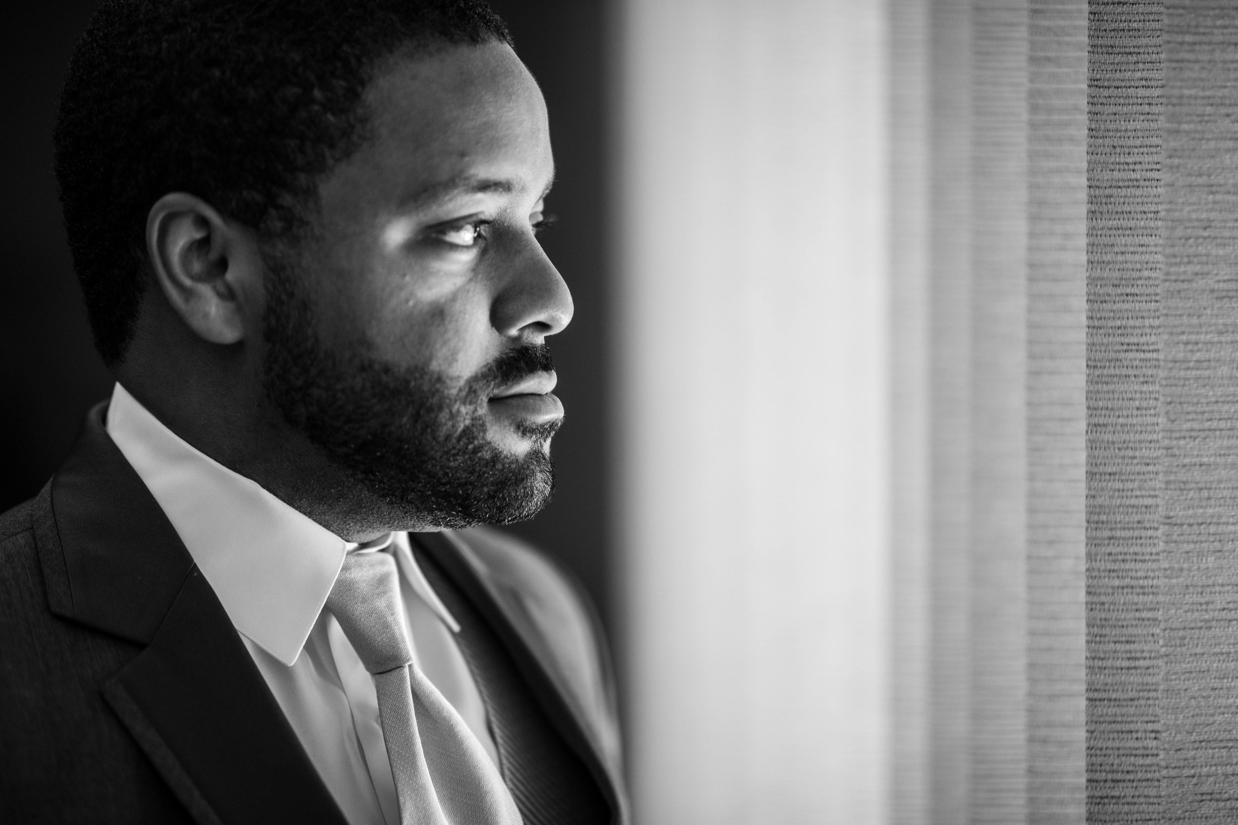  dramatic Black and White photo of the groom looking out of a window 