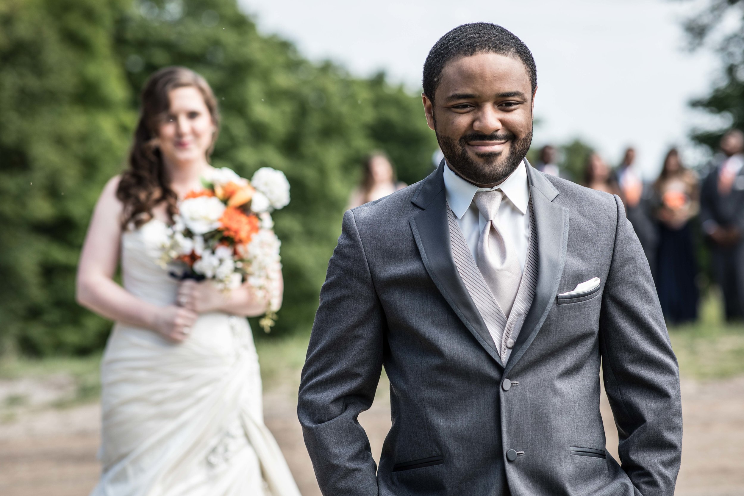  The bride walks up behind the groom as he smiles in anticipation for the first look 