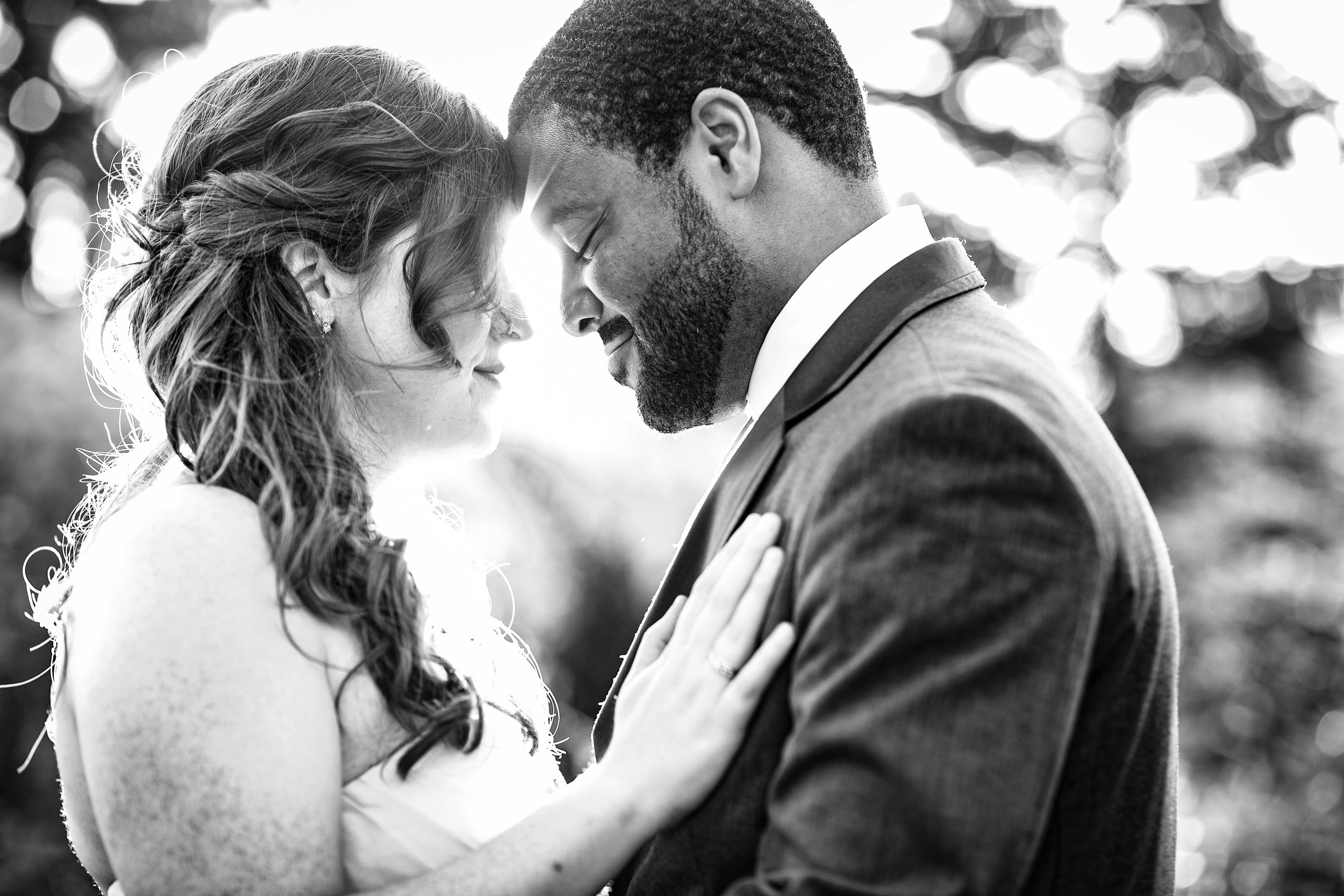  black and white close up of bride and groom with sunset behind them 